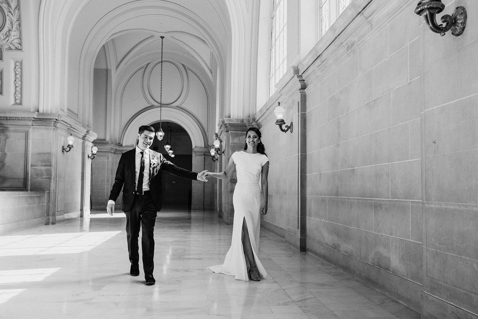  bride and groom walking down the hall in black and white  