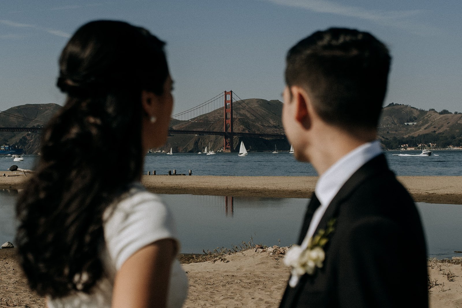  bride and groom on beach looking across to the golden gate bridge  