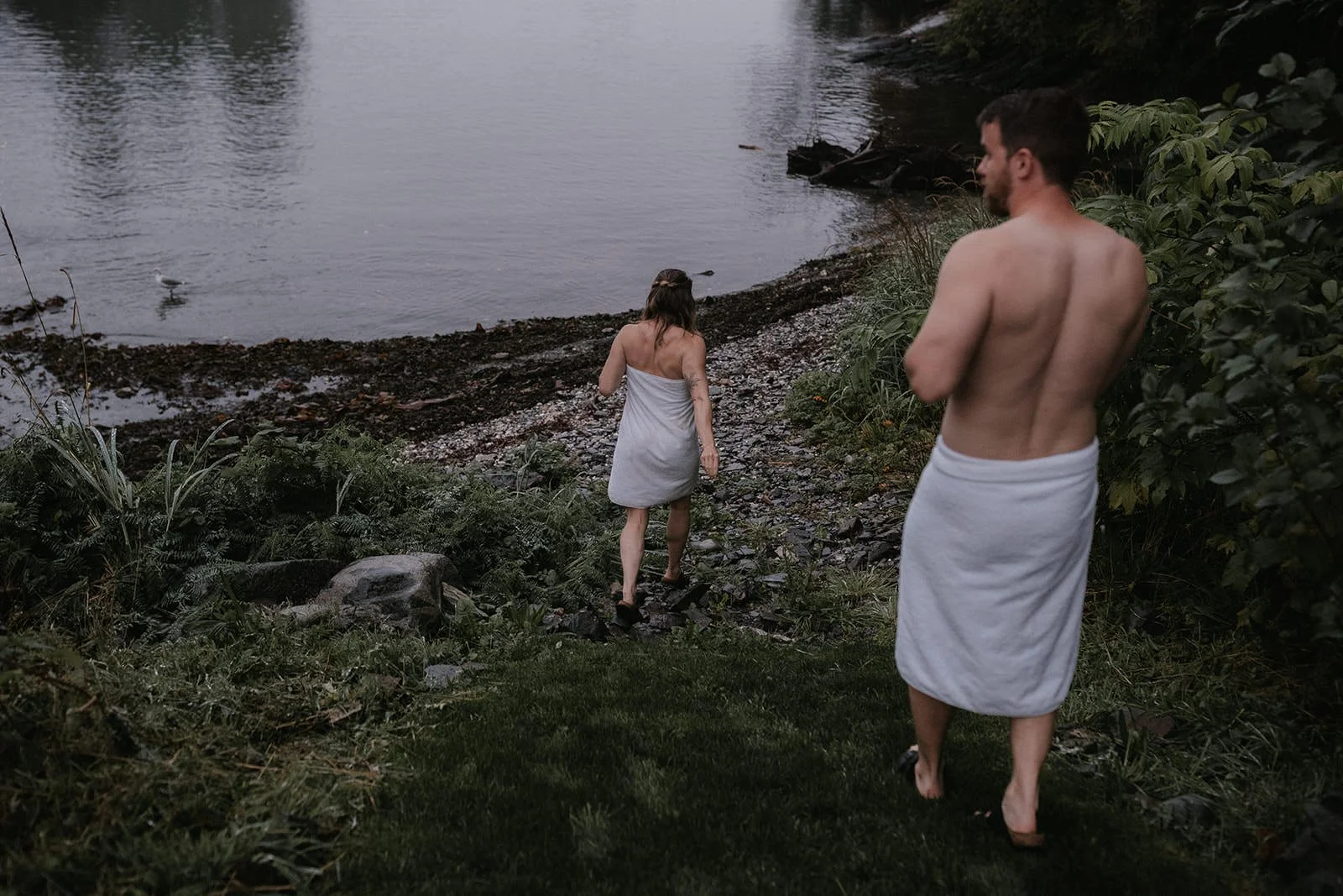 two people in towels walking towards water