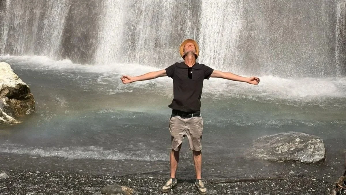 Laurence pausing at a mountain waterfall during Alptitude 2026