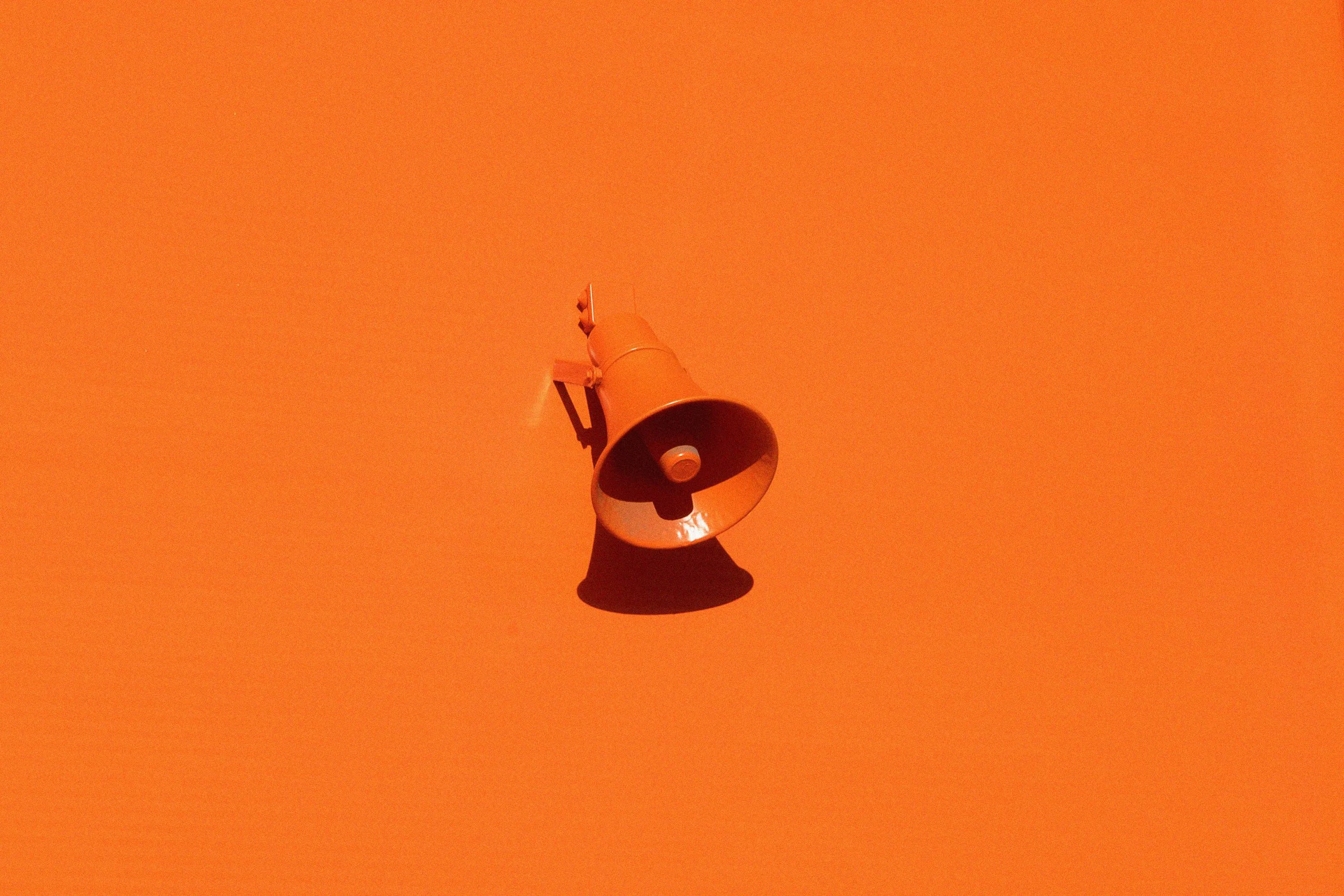 Orange wall with a mounted orange megaphone speaker.