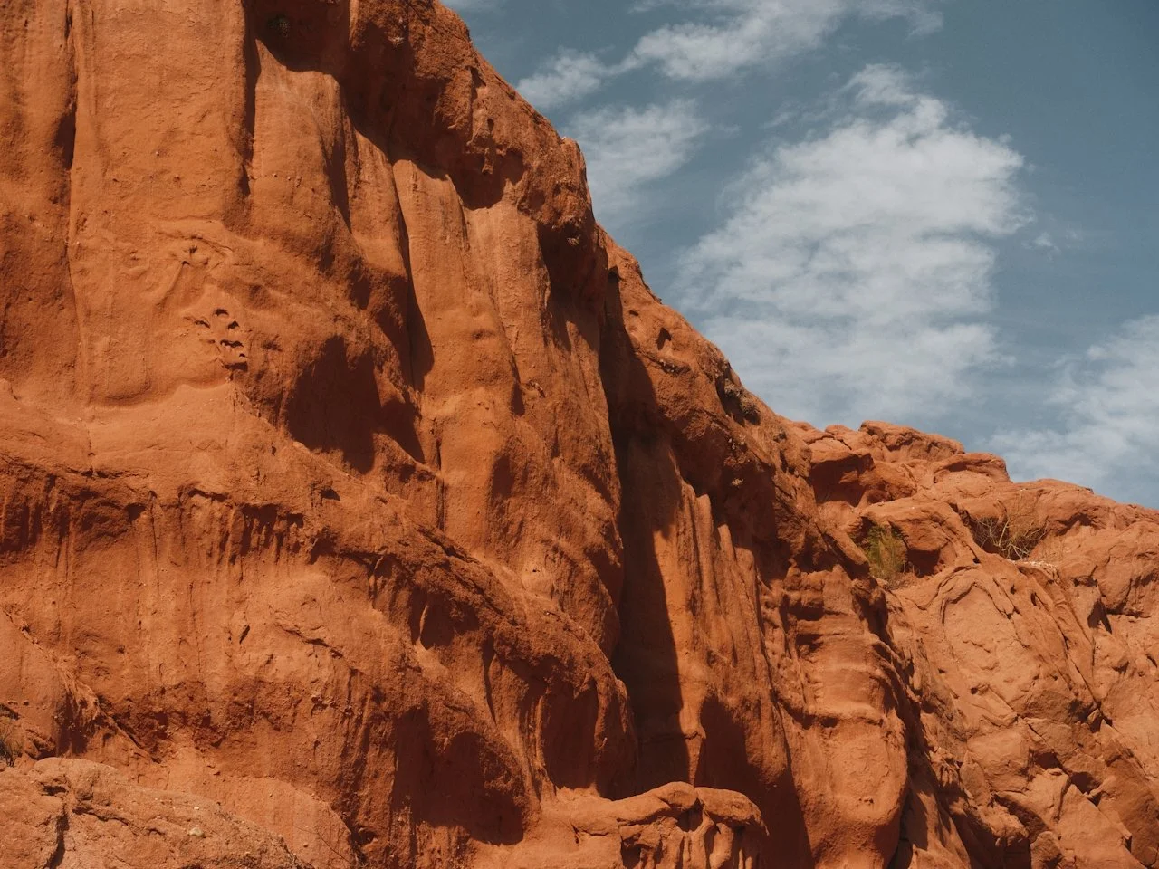 Red rock cliffs under a partly cloudy sky.