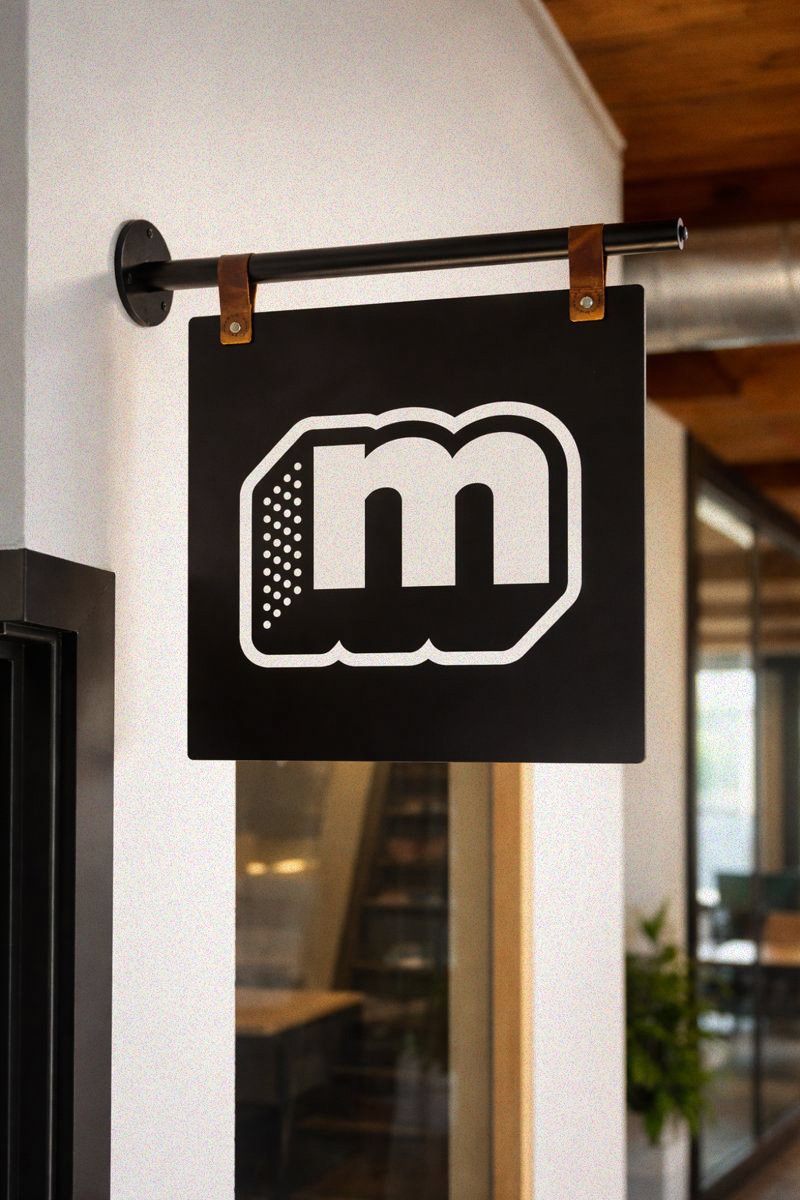 Black sign with a white cookie logo hanging from a metal rod, with leather straps