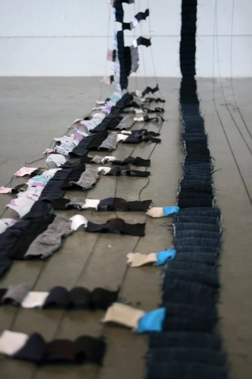 Colorful socks and gloves arranged on a wooden floor, reflecting in a mirror wall.