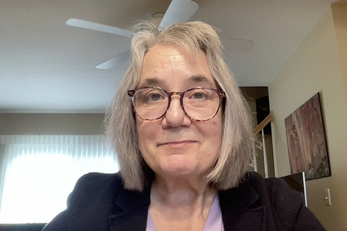 Leslie, a white woman with straight blonde hair and glasses, looks into the camera