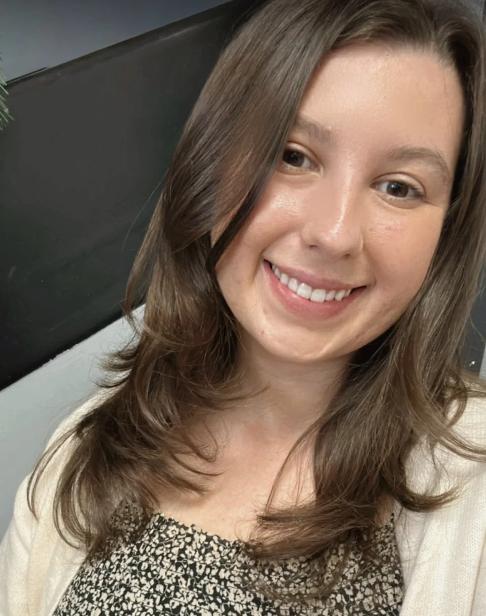 Grace, a white woman with brown hair and eyes, smiles brightly