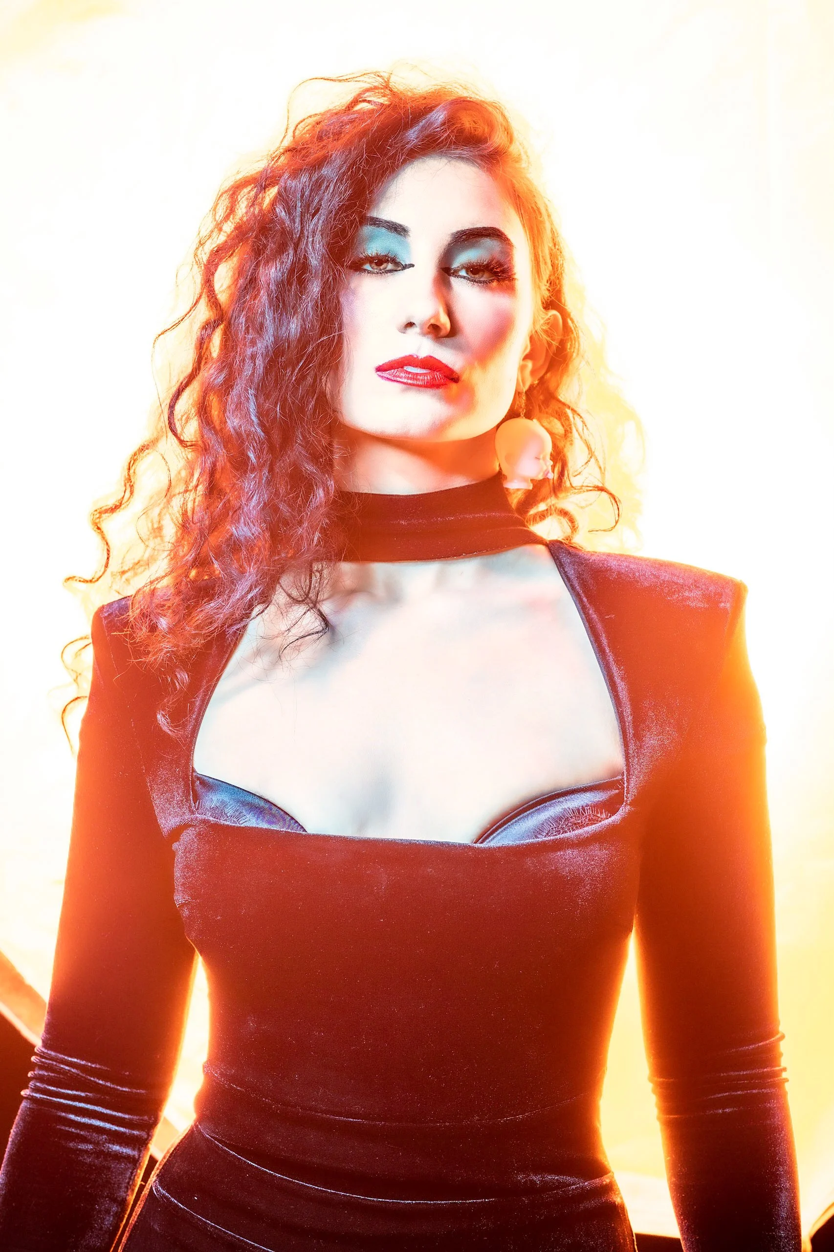 A high-key studio portrait of a professional white model dressed as a 1980's goth. The woman radiates a glowing fashion aesthetic, capturing the essence of the era.