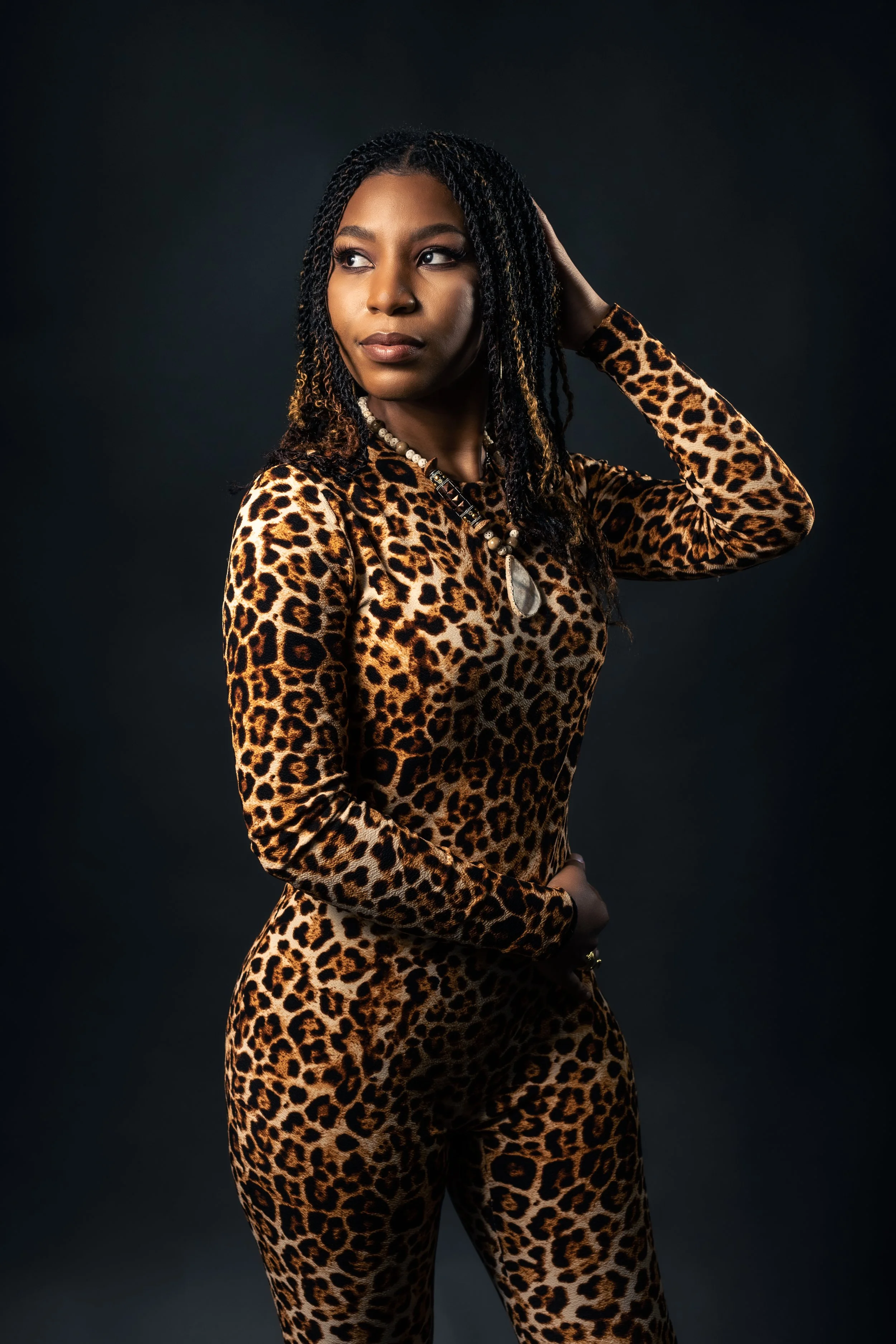 A captivating studio portrait of a black fashion model striking a confident and stylish pose. She is dressed in a chic cheetah print wardrobe, adding a touch of wild sophistication to the composition.