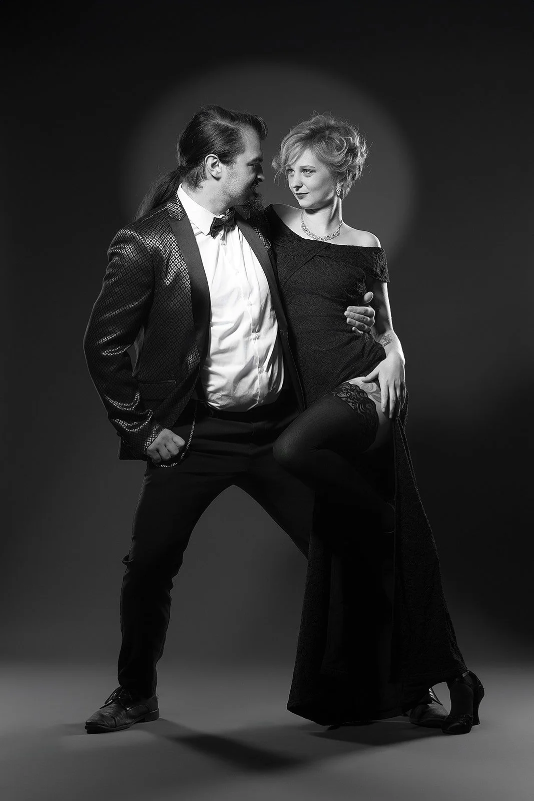 A timeless black and white Old Hollywood portrait featuring a dancing couple. The image exudes classic elegance, capturing the allure of a bygone era, with dramatic stage lighting enhancing the cinematic atmosphere.