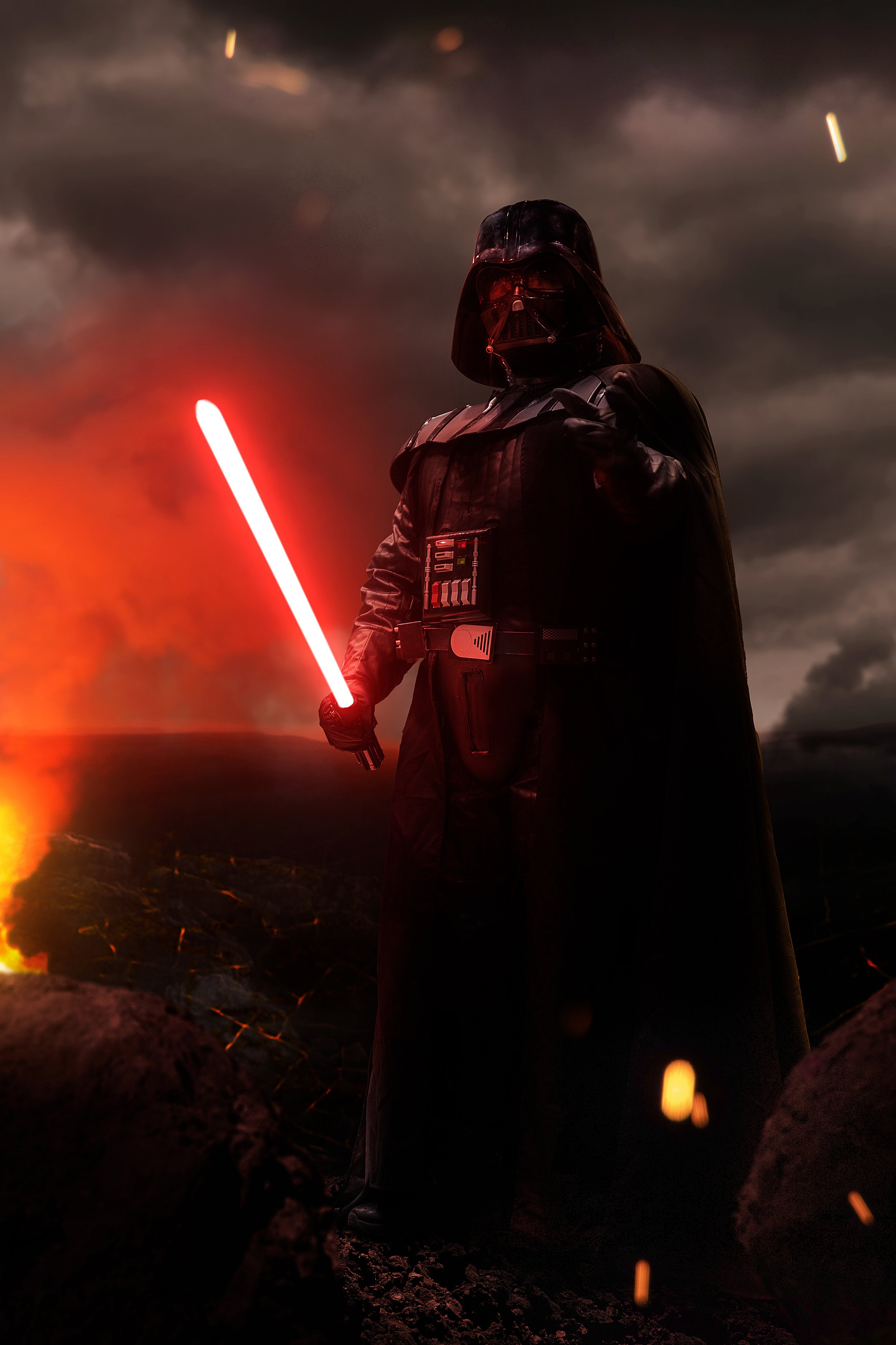 The image is a full body cosplay portrait of a man dressed as Darth Vader, the iconic Sith Lord from Star Wars. He holds a menacing red lightsaber in one hand and extends his other hand outward, as if using the Force to choke his opponent. The enviro