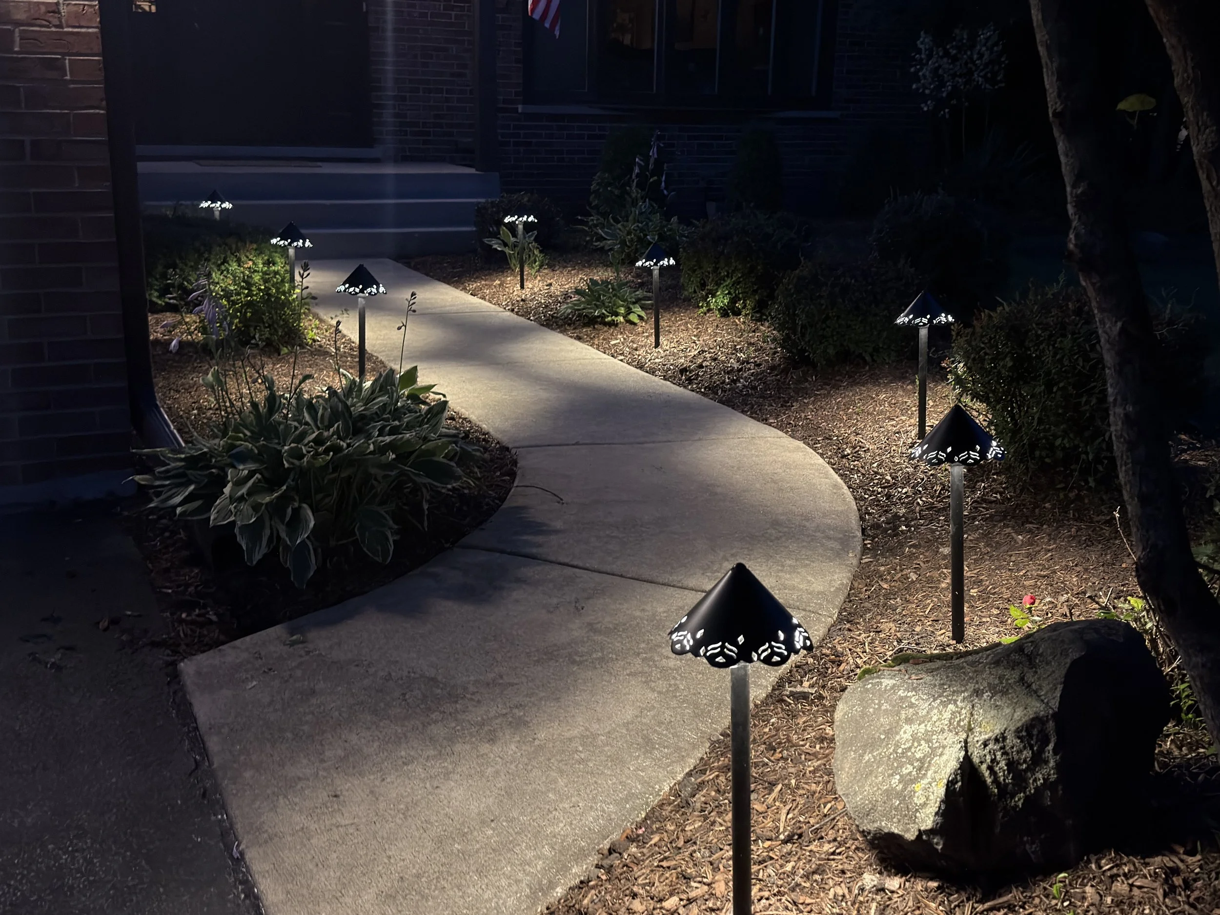 Night view across a curved walkway with several path lights creating an even pool of light through the landscape.