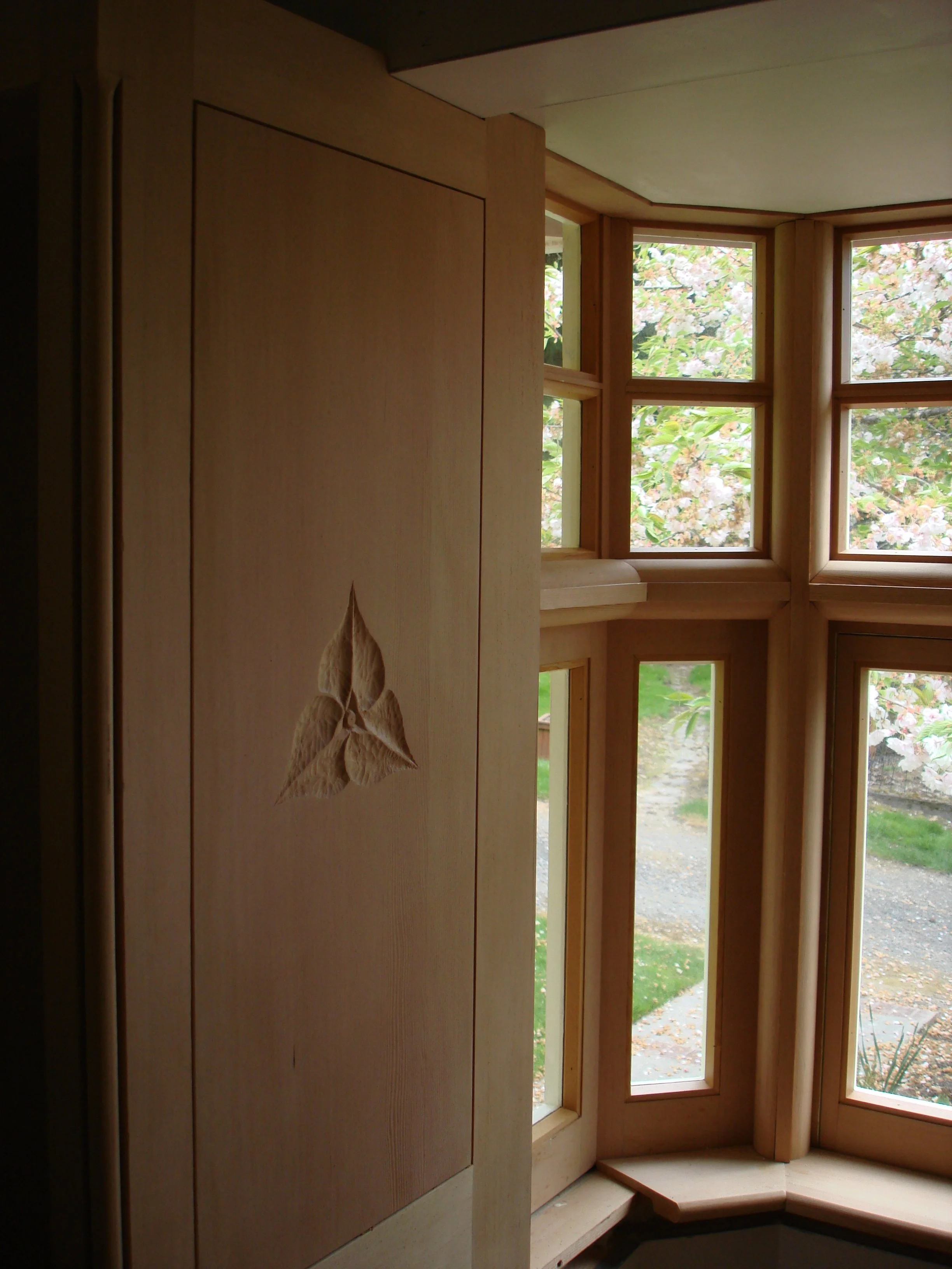 Bay window in the style of CFA Voysey at Goddards. The wall paneling is doug fir with a pair of trilliums carved on them.