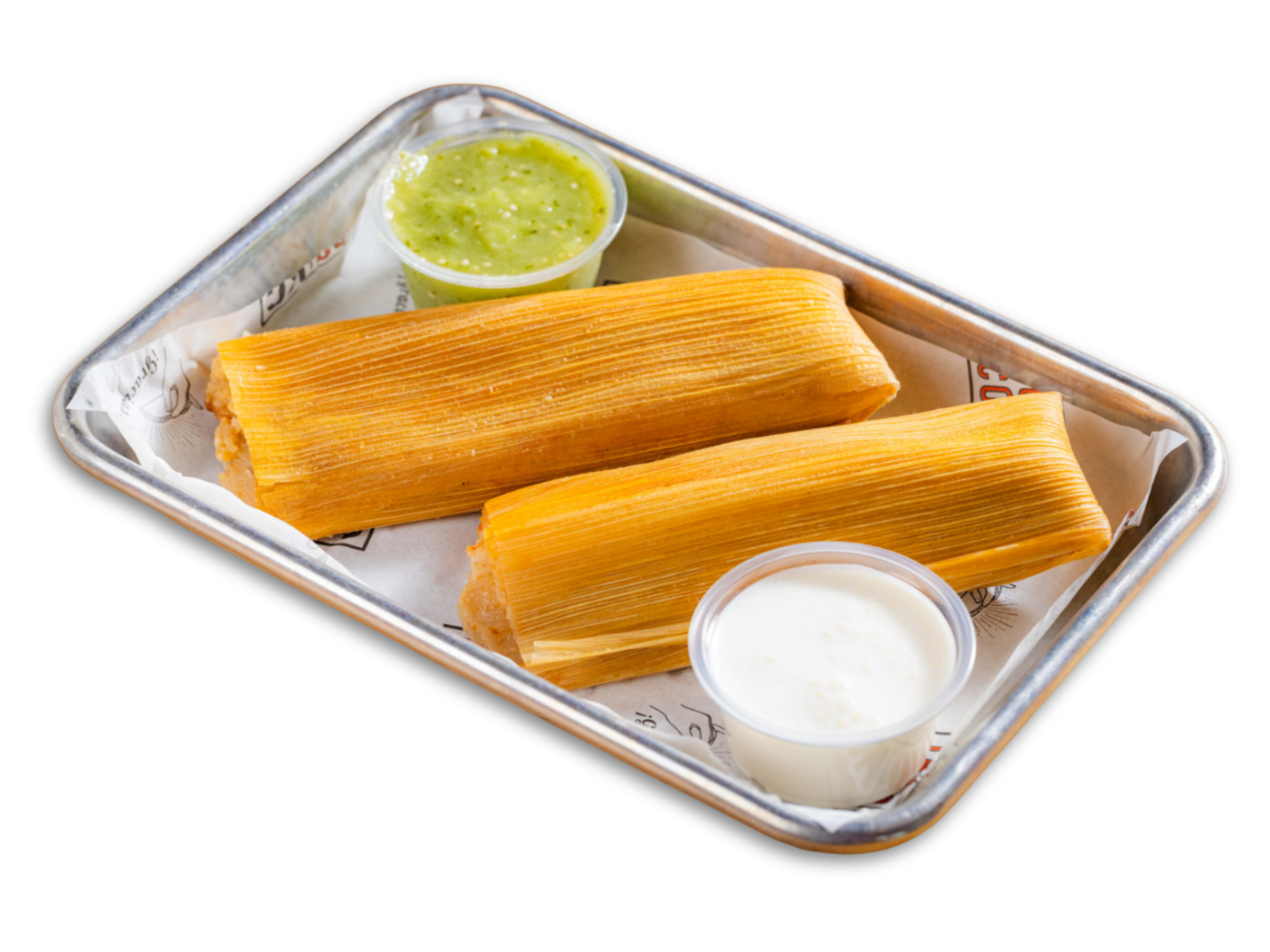 Two tamales on a metal tray with green and white sauces in cups.