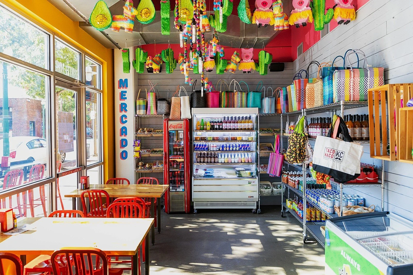 Colorful interior of TACO NACO KC Westport with dining tables, red chairs and Mexican piñata decorations.
