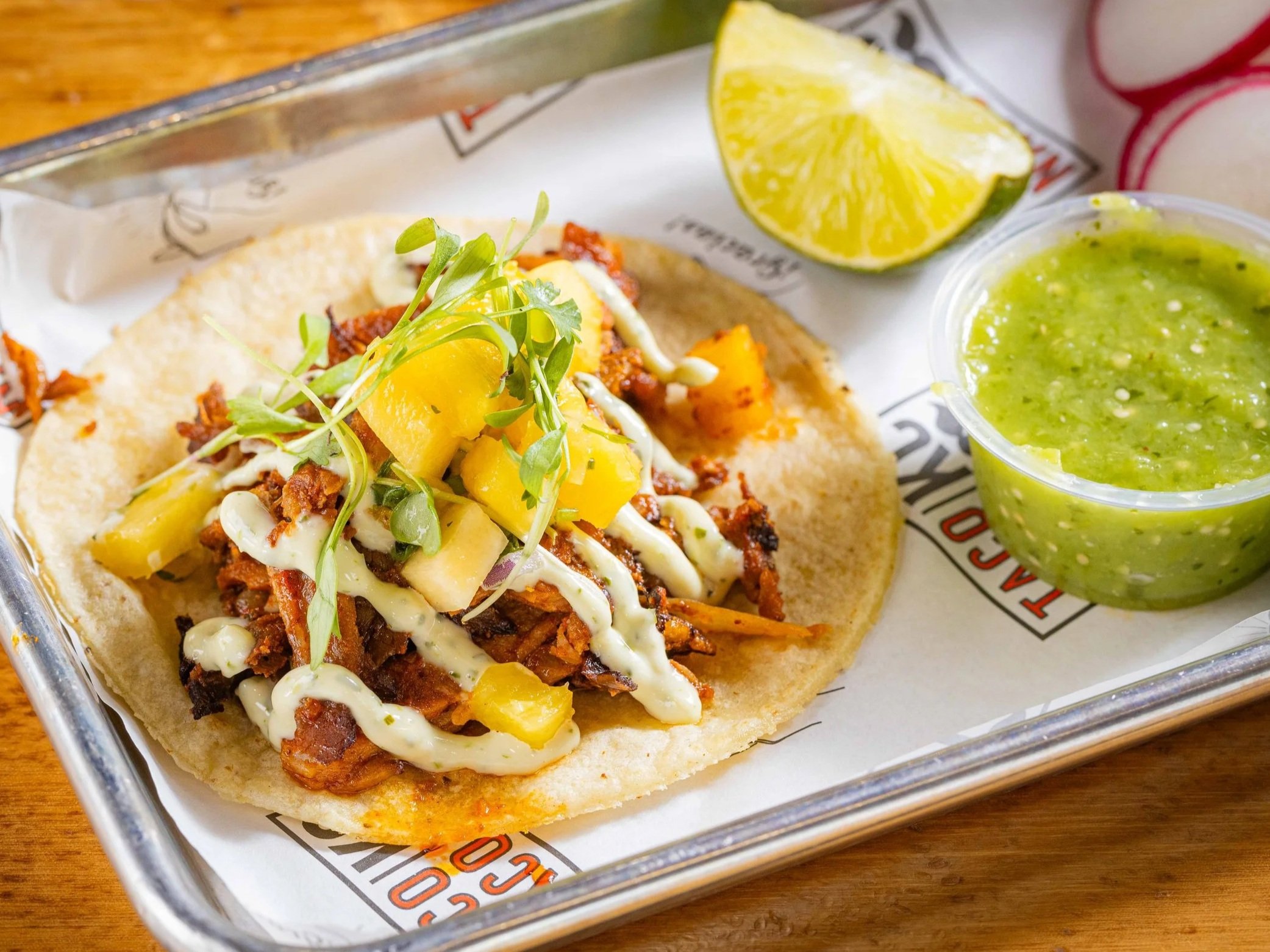 Taco al pastor topped with pineapple, onion and cilantro