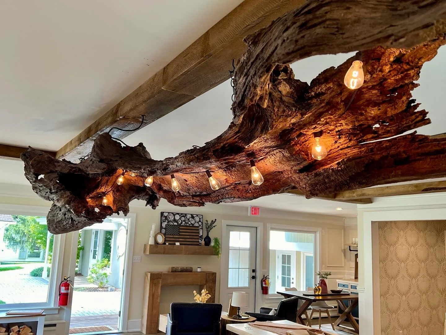 Interior of a room with a rustic wooden chandelier made from a large, irregularly shaped piece of wood with hanging light bulbs.