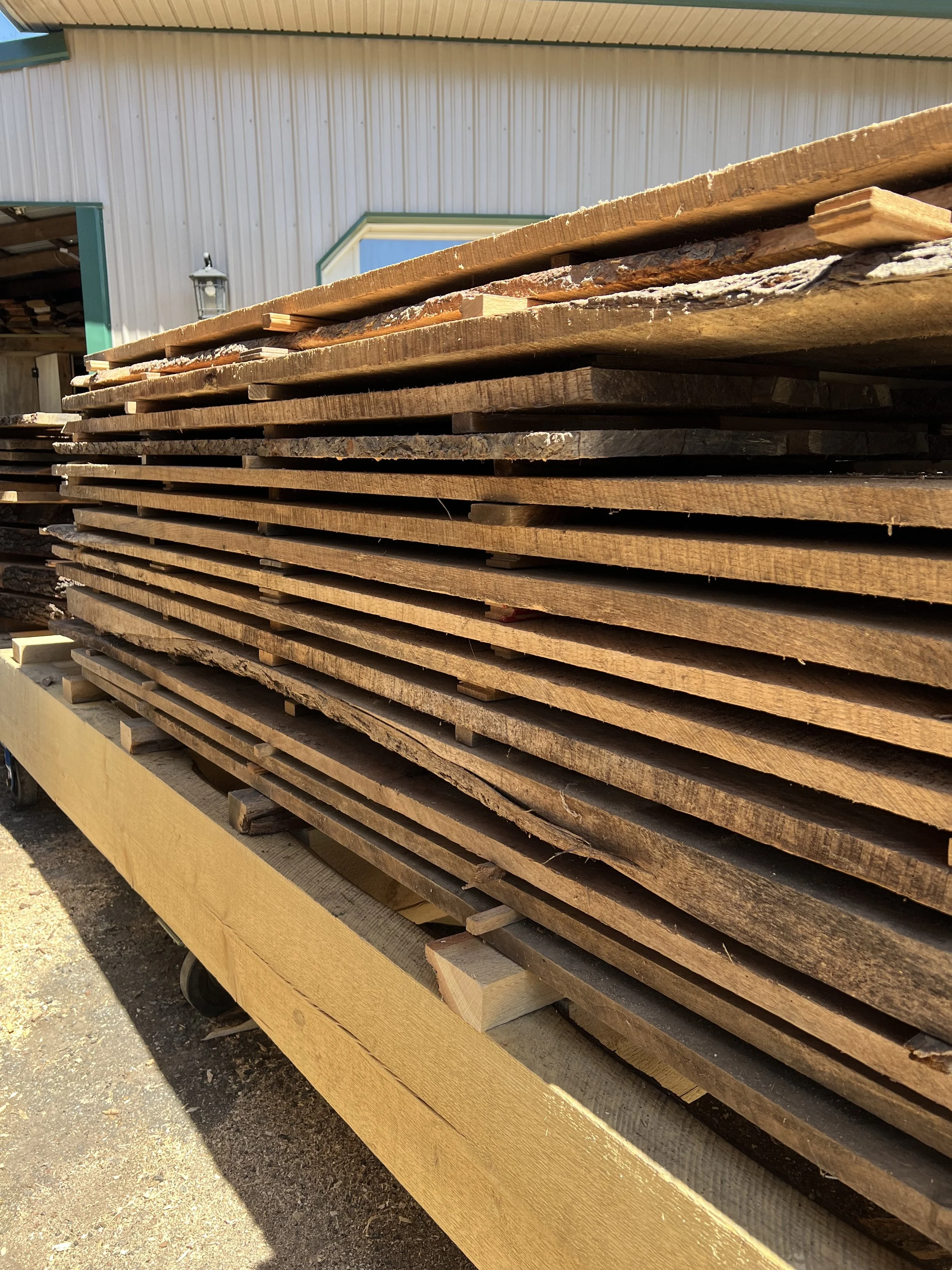 Stack of wooden planks on a dolly outside a building.