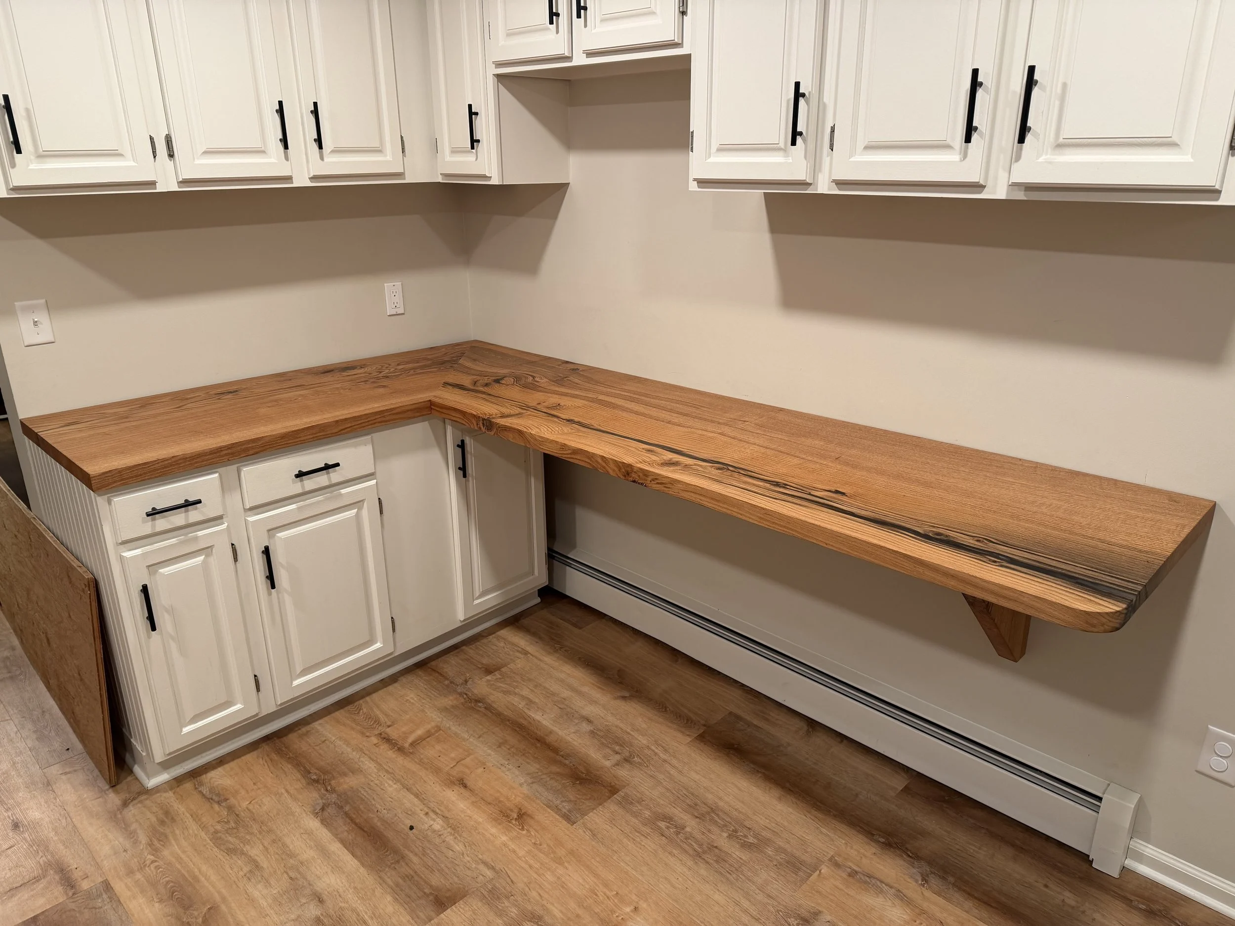 Kitchen with white cabinets, a wooden countertop, and a wooden floor.