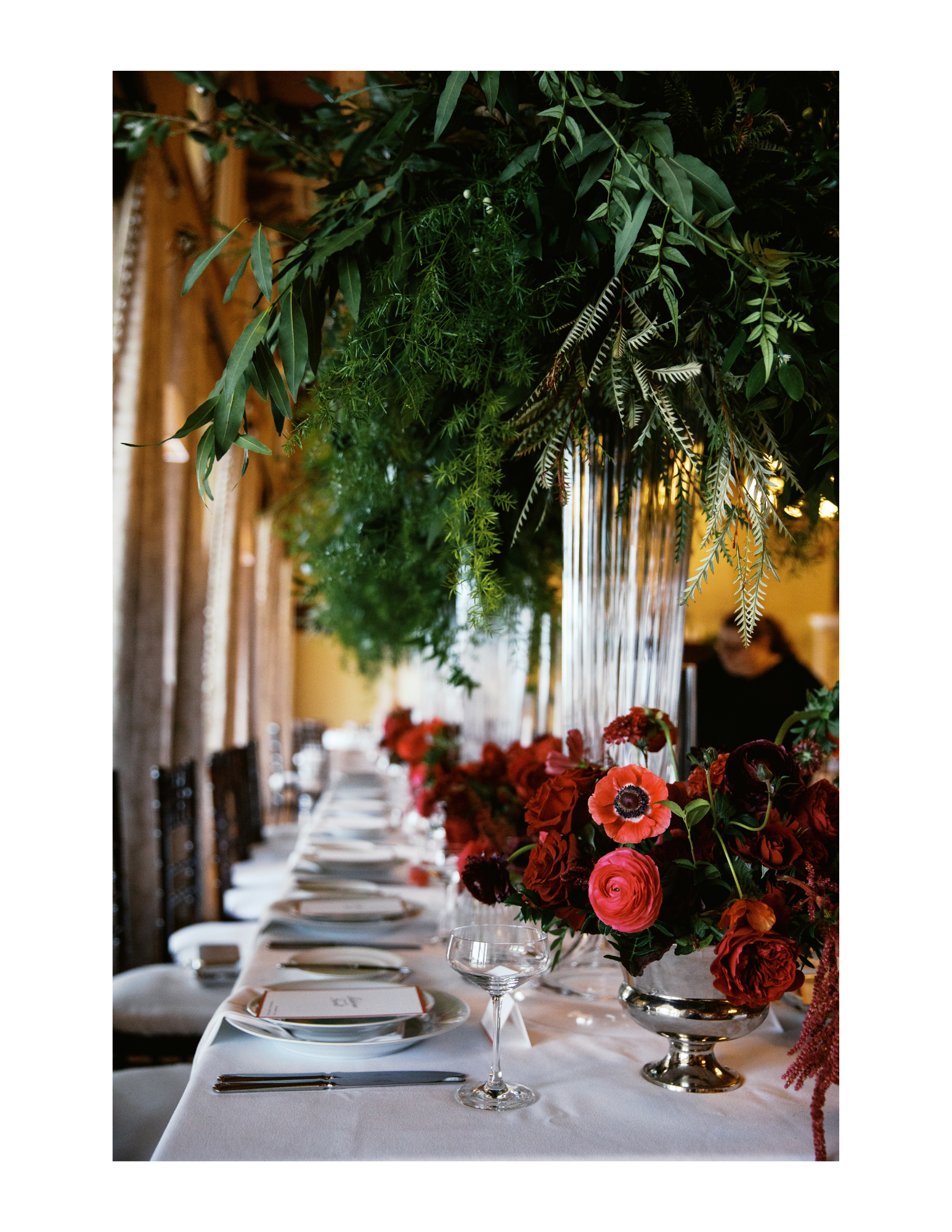 Reception table centerpieces featured red carnations, silver dishes, tall glass vases and greenery. Photograph taken by wedding photographer Sheridan Mangold at Congressional Country Club in Bethesda, MD.
