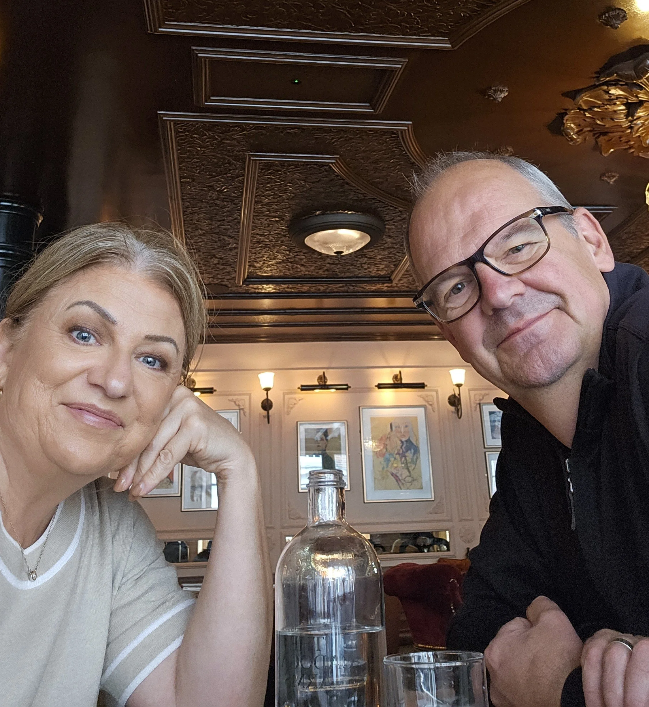 Canadian couple smiling at camera in an elegant vintage  london restaurant with ornate copper ceiling