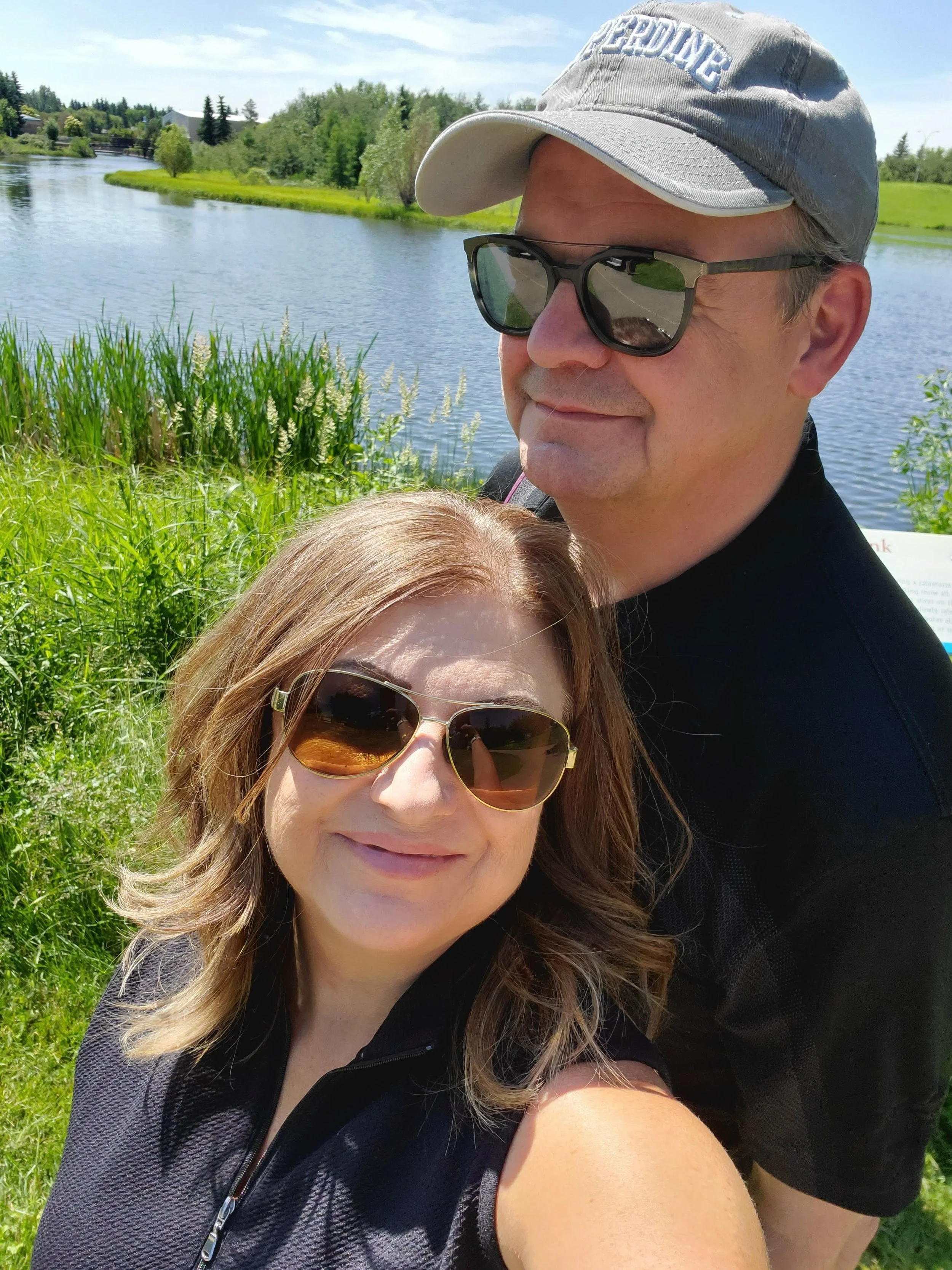 Happy GenX couple smiling by the lake in Sherwood Park Alberta on a sunny summer day