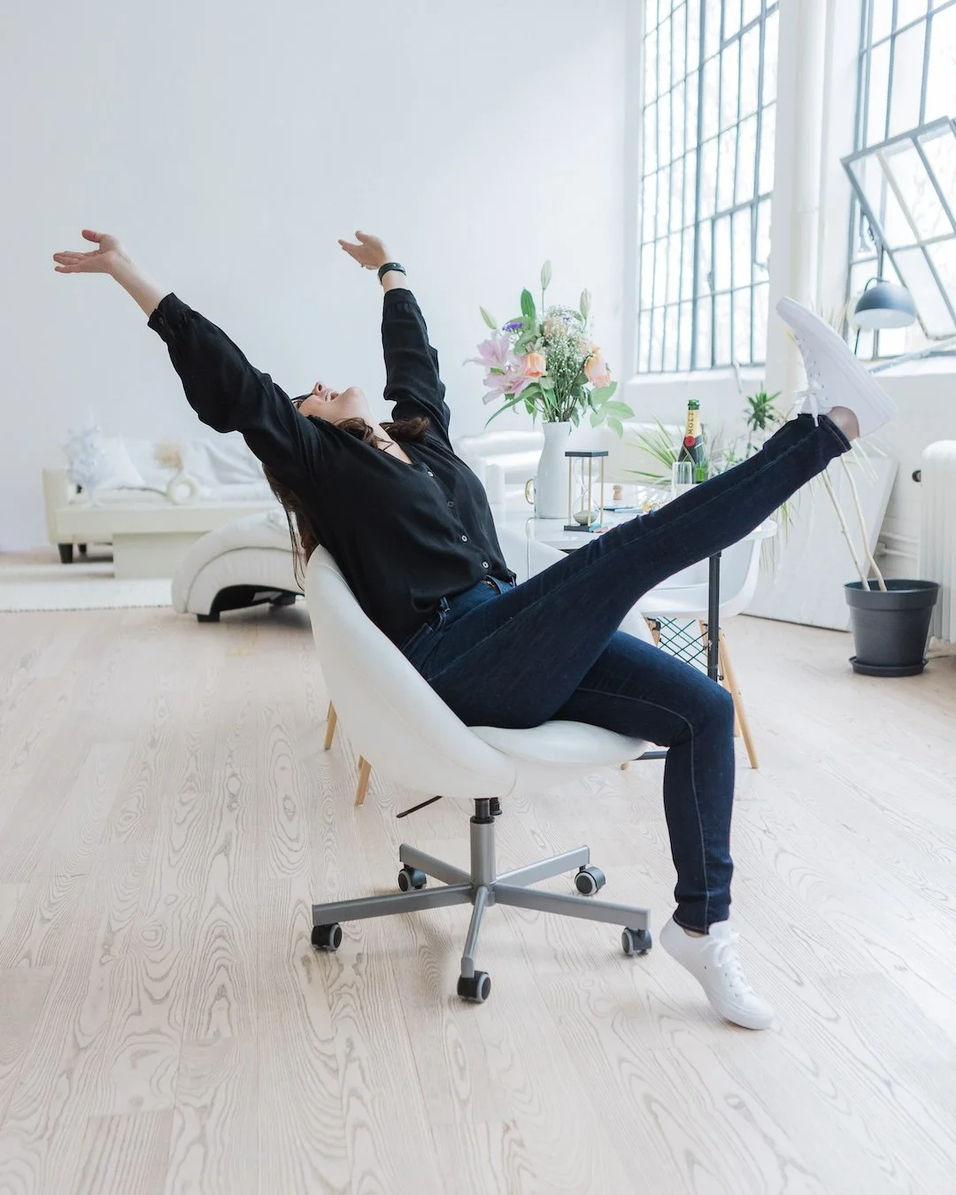 Woman sitting in a chair throwing up her hands and feet in celebration