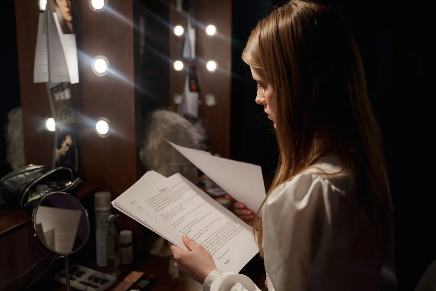Actress reading over lines backstage in front of a mirror