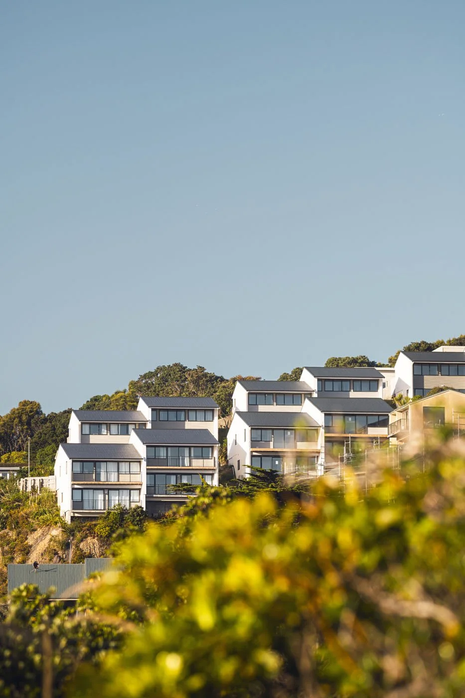 Modern houses on a hillside with a clear blue sky overhead.