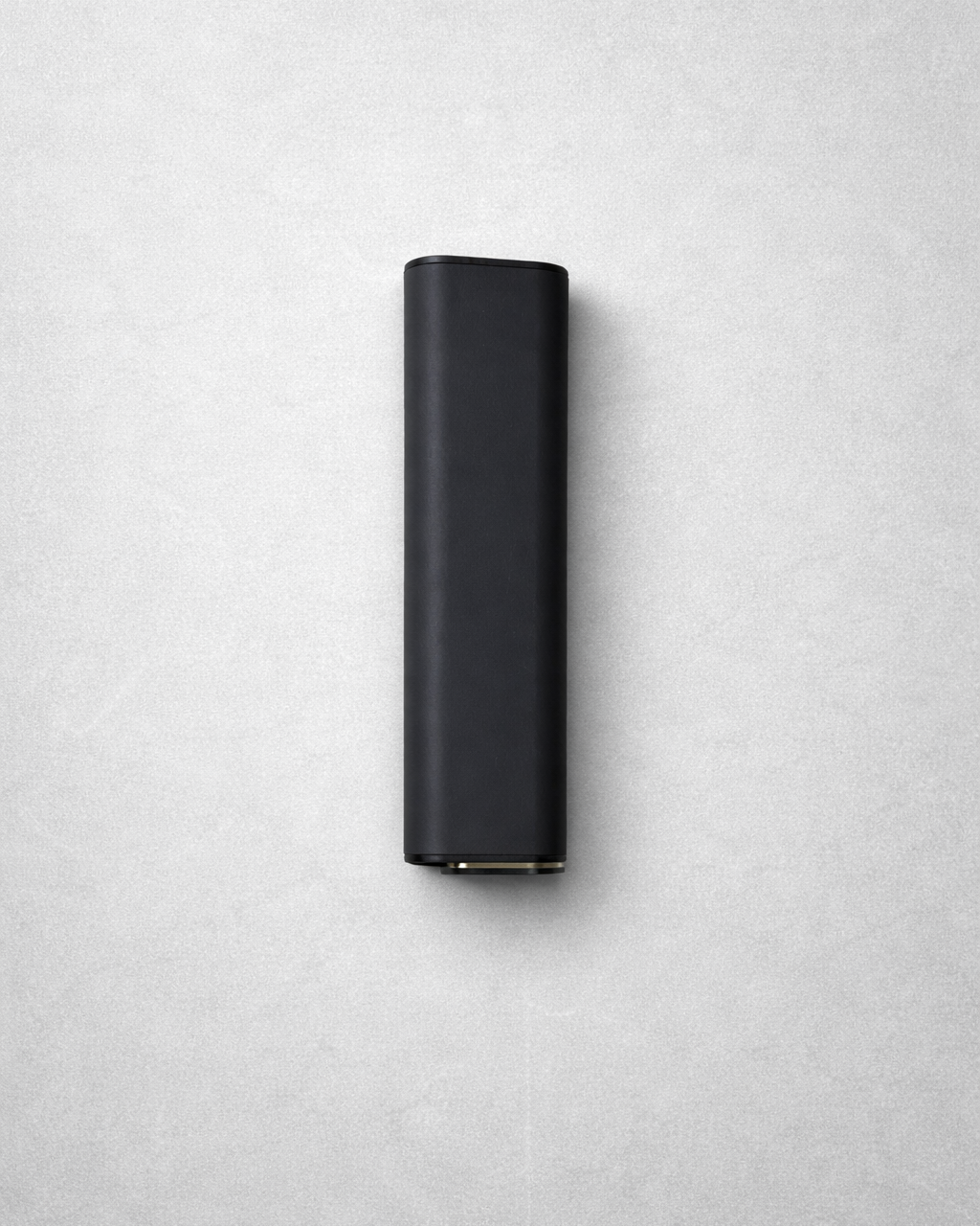 A black cylindrical device placed vertically on a light gray surface.
