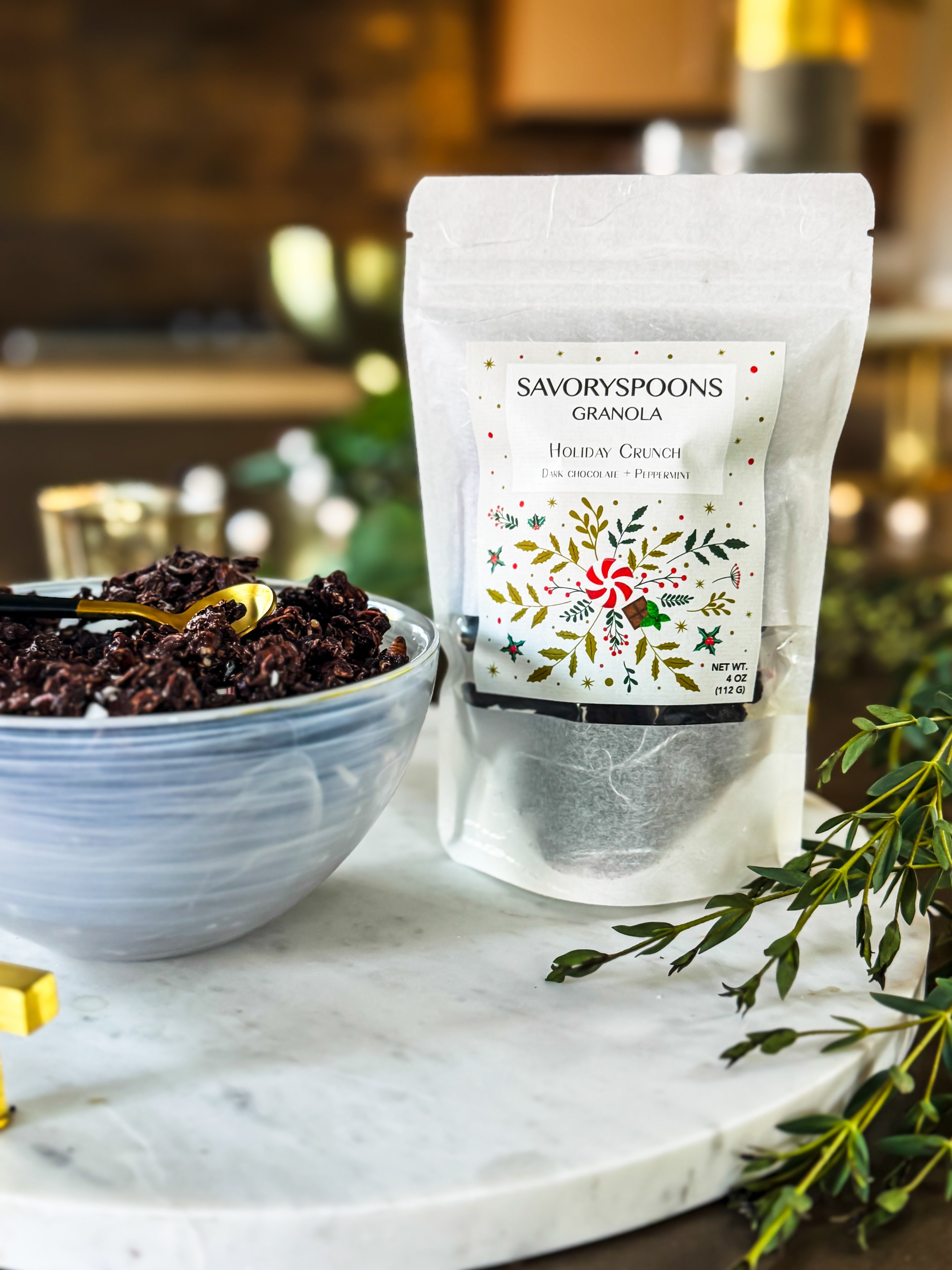 SAVORYSPOONS HOLIDAY CRUNCH GRANOLA IN BAG WITH WHITE BOWL OF GRAOLA AND GOLD SPOON.JPG