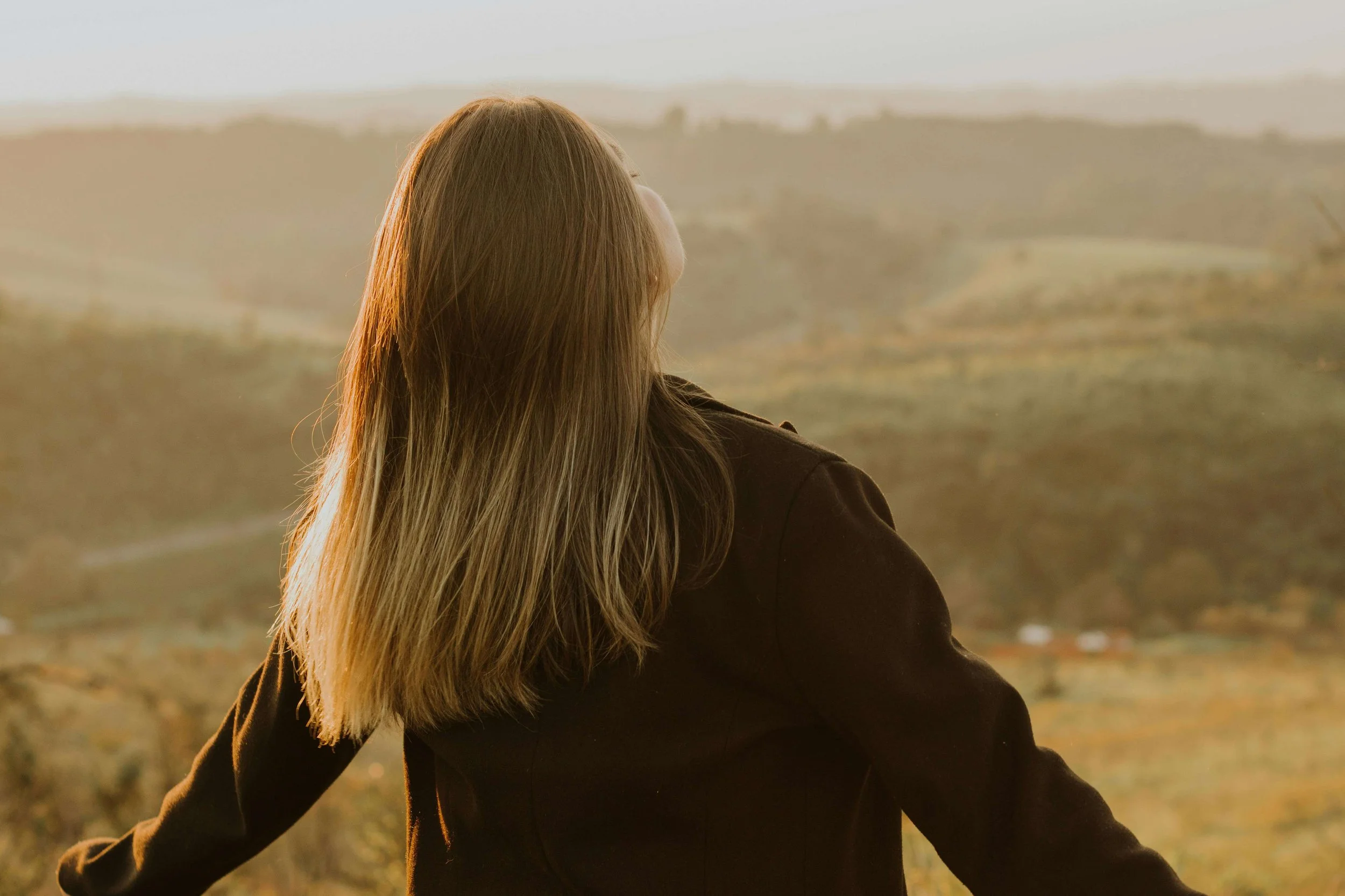 Woman outdoors at sunset with her arms outstretched, symbolizing regulation and freedom supported by somatic experiencing for nervous system dysregulation in Carlsbad, CA.