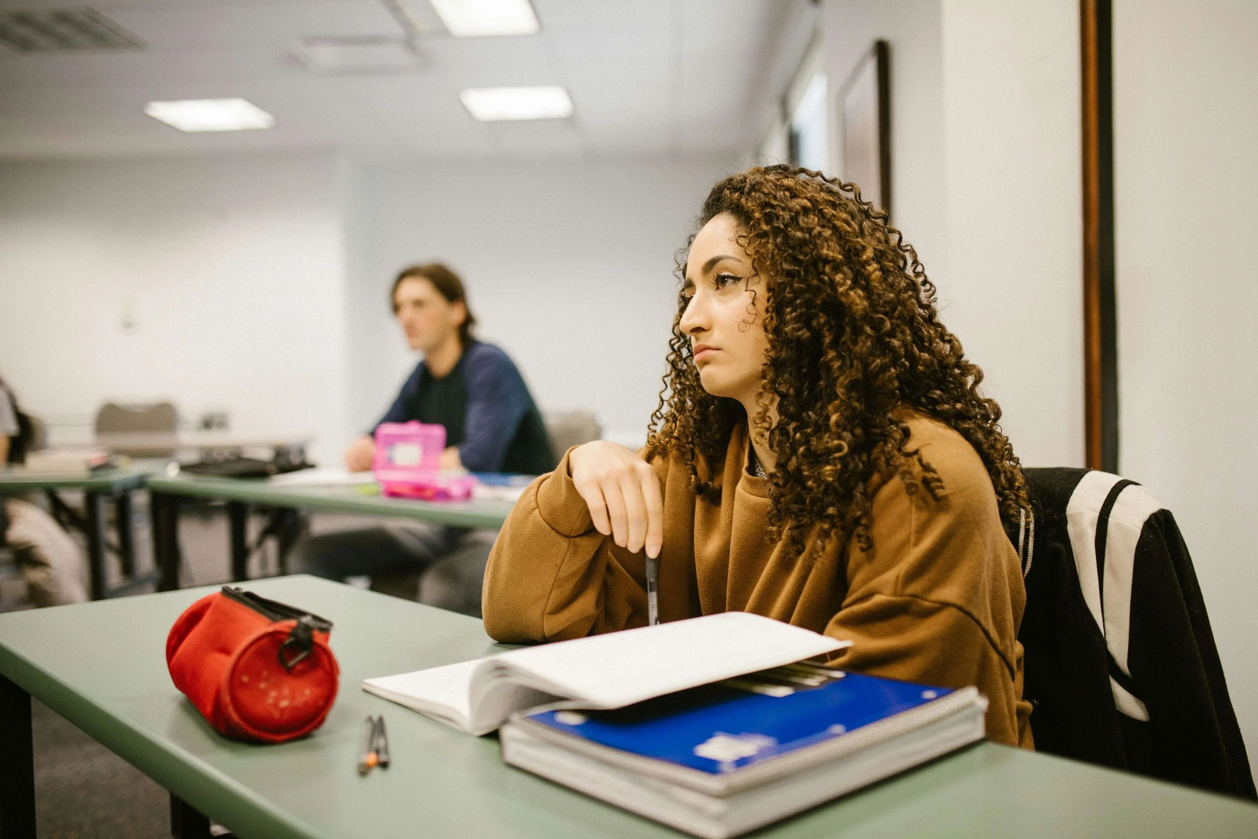 Woman sitting in a college class looking spaced out, illustrating challenges addressed through somatic experiencing for functional freeze in Carlsbad, CA.