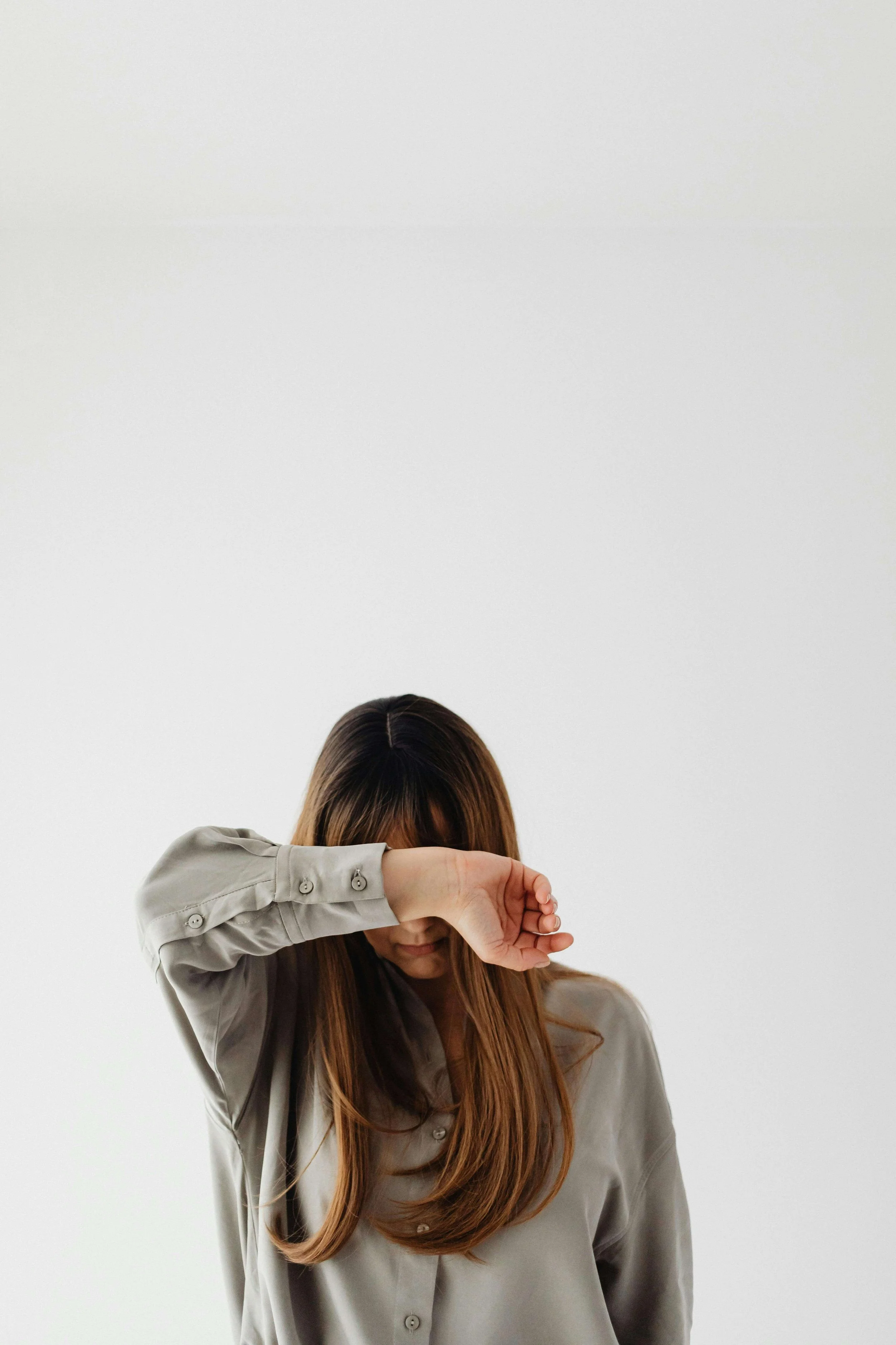 Woman covering her face with her arm, representing protective responses explored in somatic trauma therapy in Carlsbad, CA.