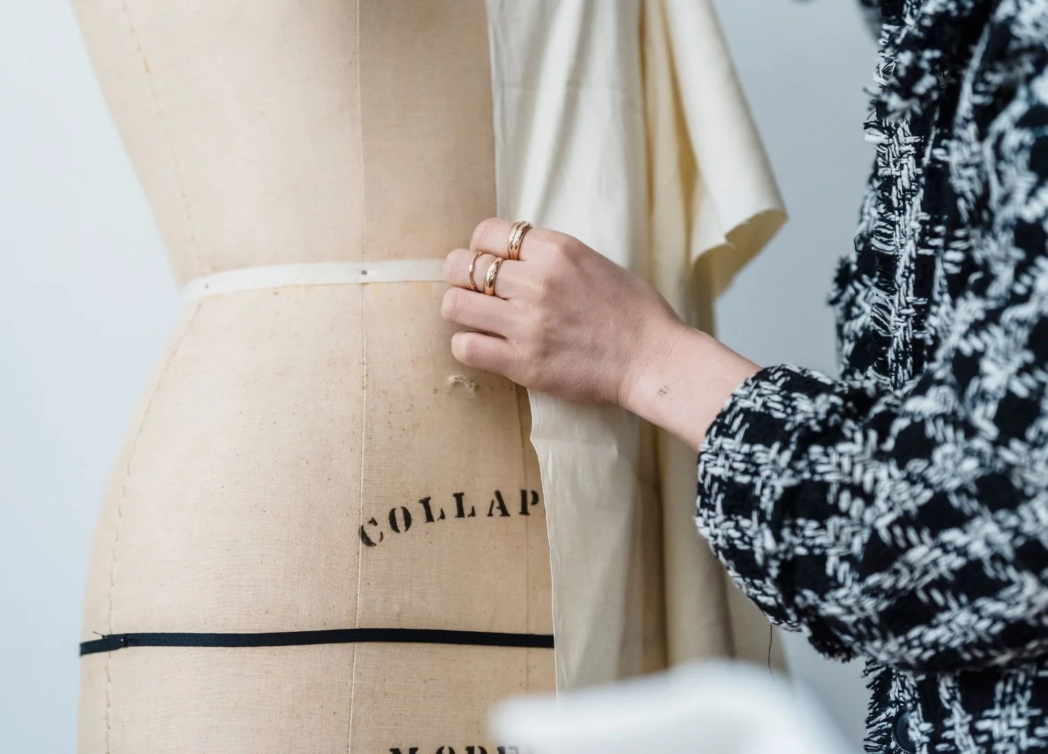 person in black and white plaid, is shown draping muslin on a dressform