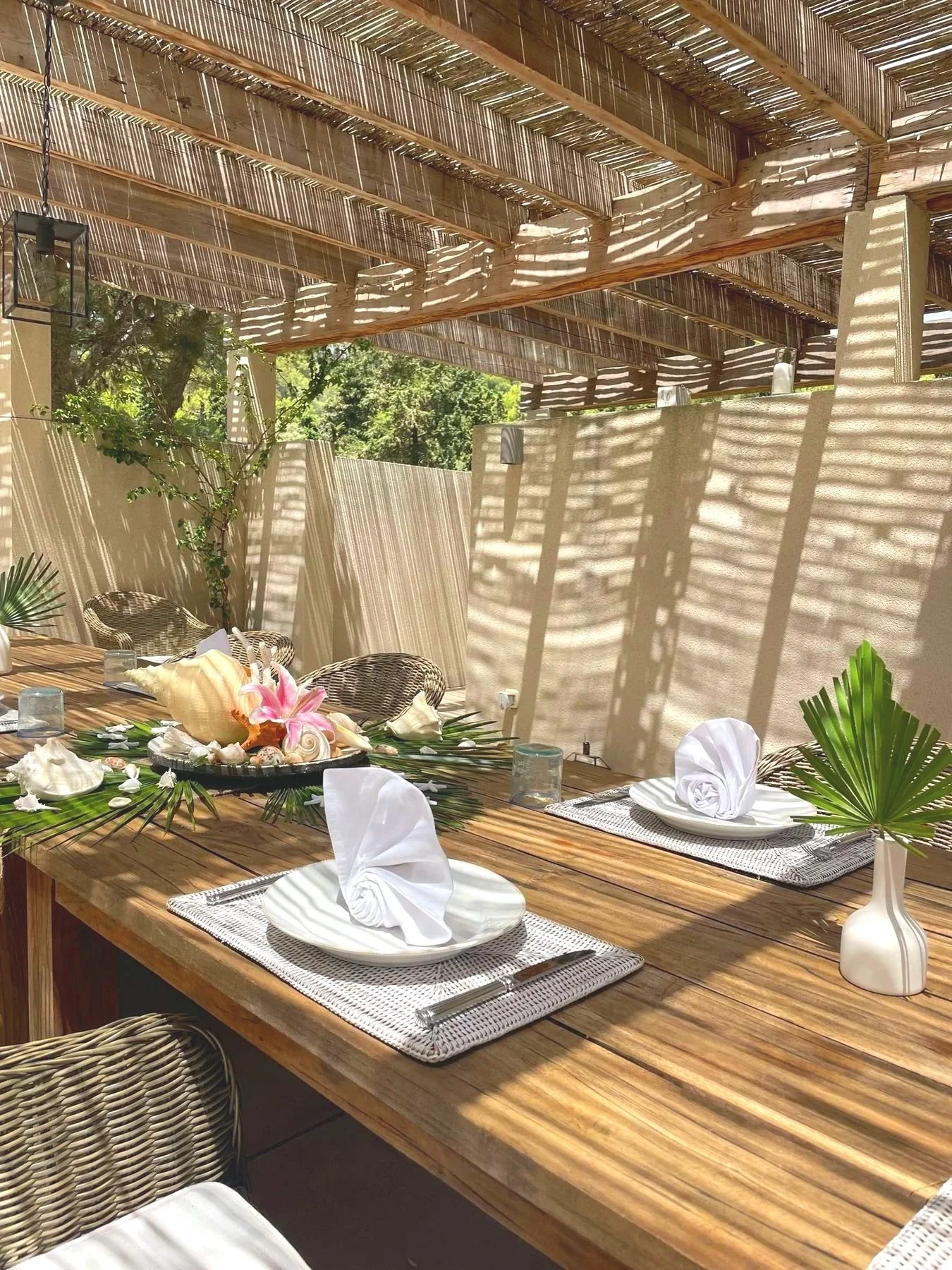 Pergola dining table with white plates, folded napkins and fresh flowers, set by Bluelime Bespoke in Mallorca