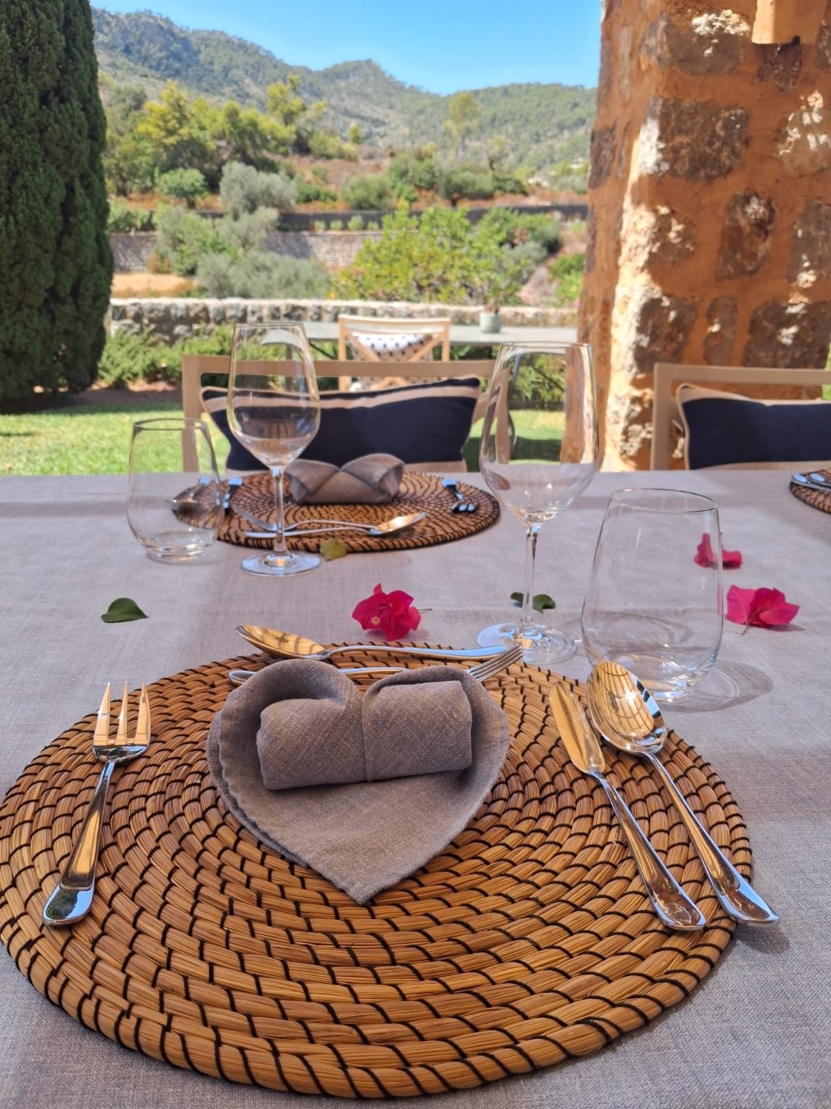 Rattan chargers and folded linen napkins on a table set for a private chef lunch in Mallorca