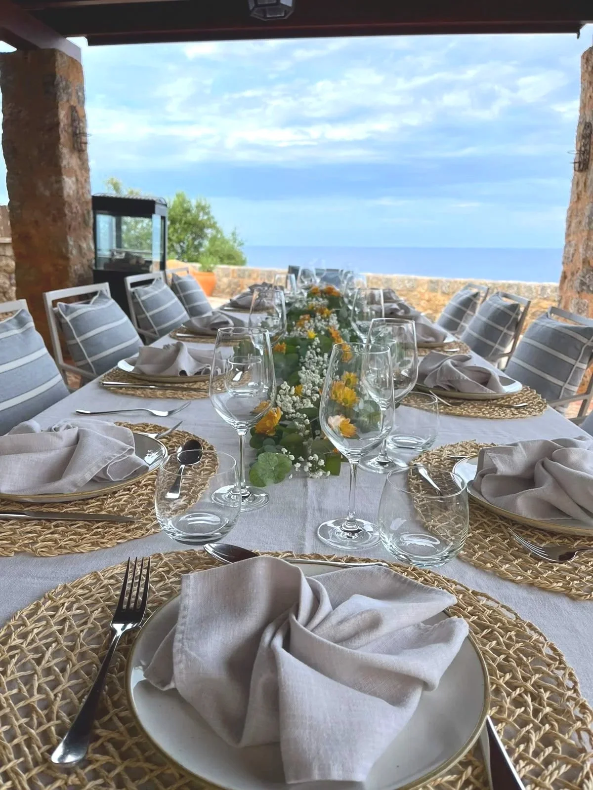 Celebration tables with linen napkins and woven chargers overlooking the sea in Mallorca