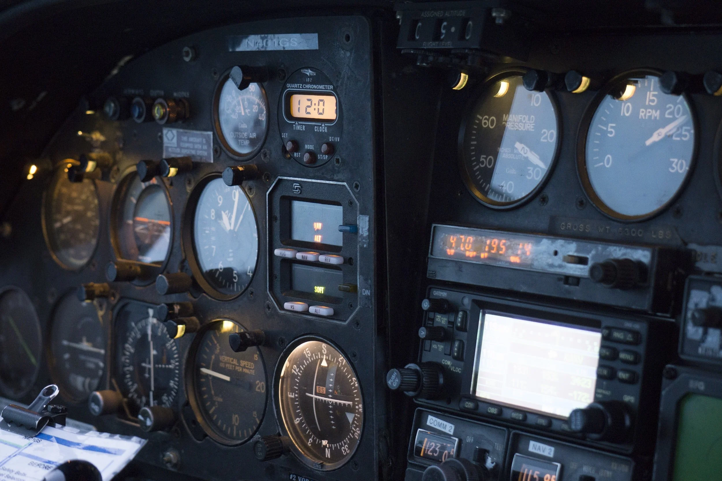 Close-up of an aircraft cockpit instrument panel showing various gauges, switches, and digital displays, including altimeter, airspeed indicator, and communication radios.