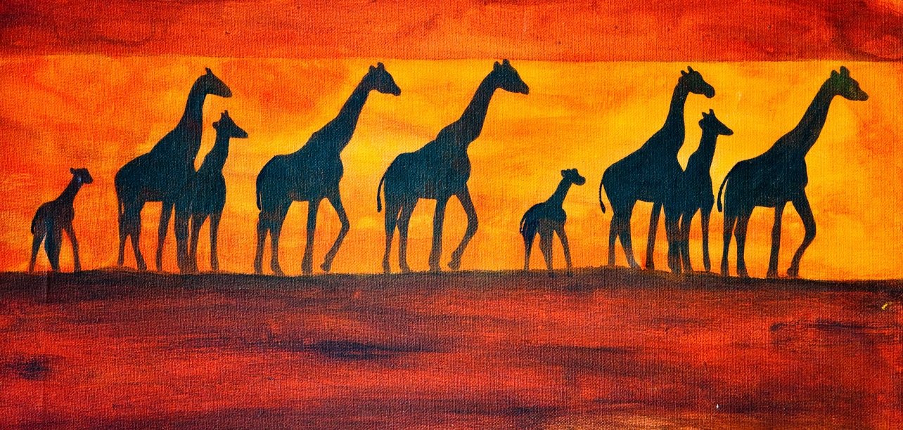 Silhouetten von Giraffen vor einem orangefarbenen Sonnenuntergangshimmel.