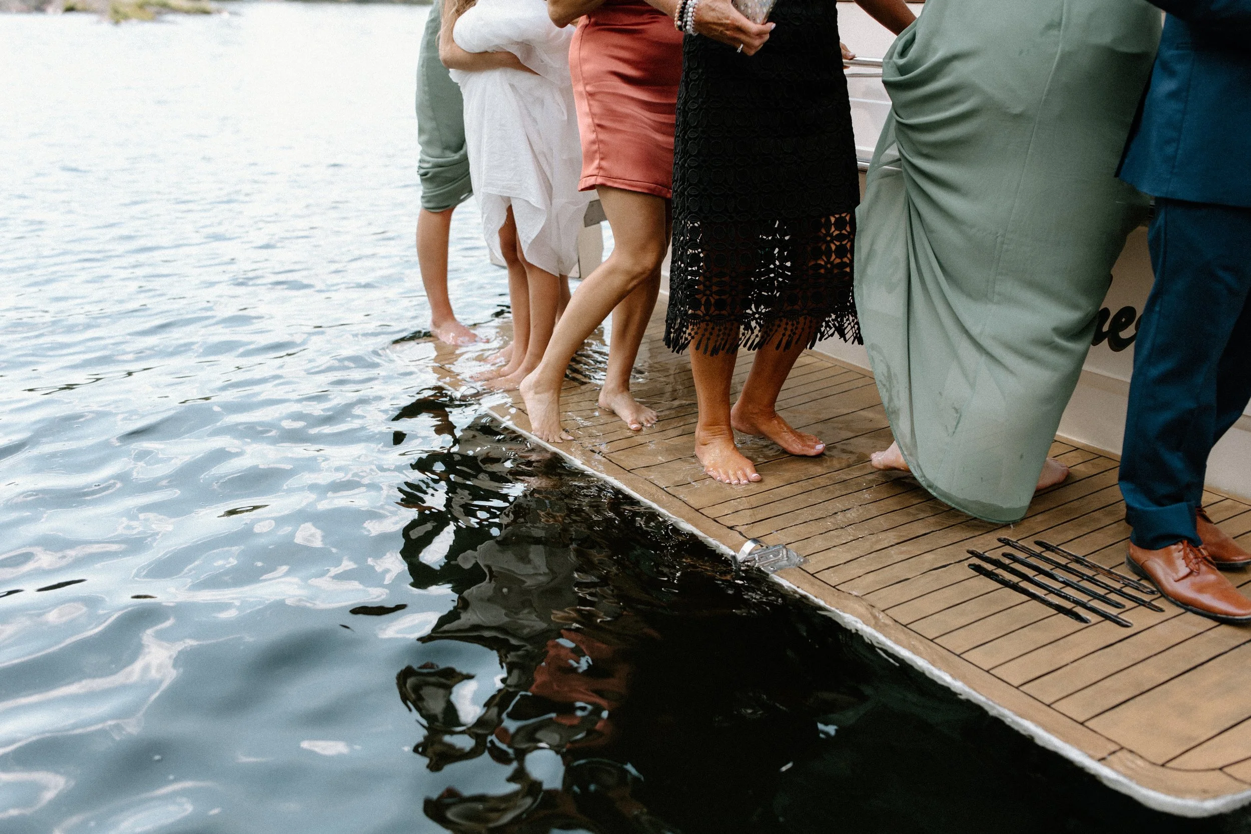 People standing on the edge of a boat with their feet in the water.