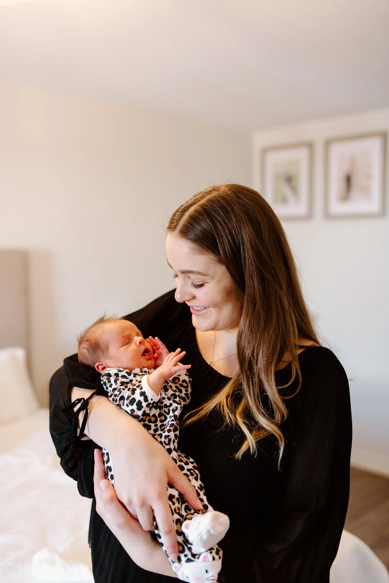 A woman holding a newborn baby inside a bedroom.