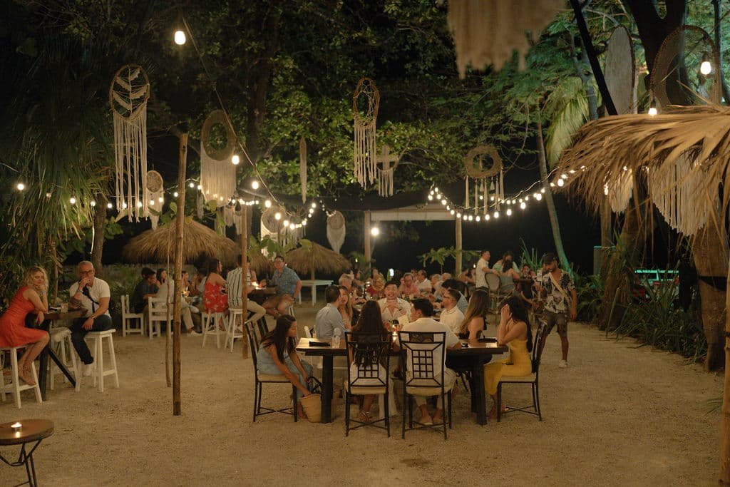 welcome party for a destination wedding in Costa Rica, guests having dinner outside under lights