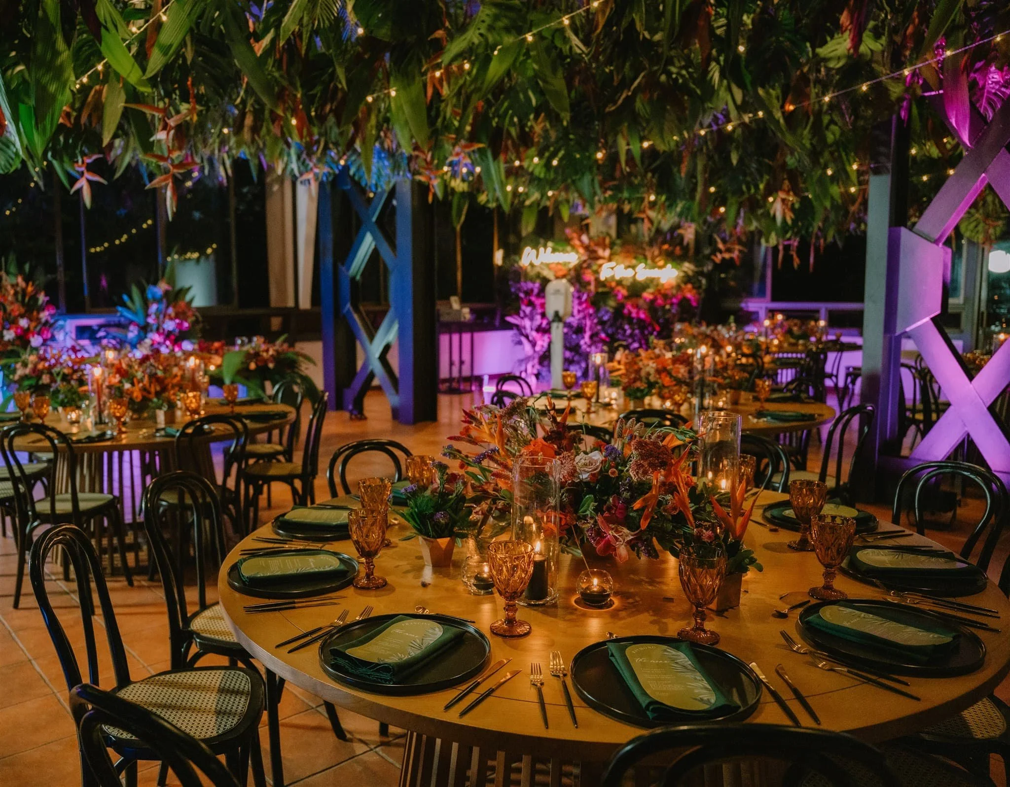 elaborate, colorful, and floral heavy reception design with greenery overhanging from the ceiling