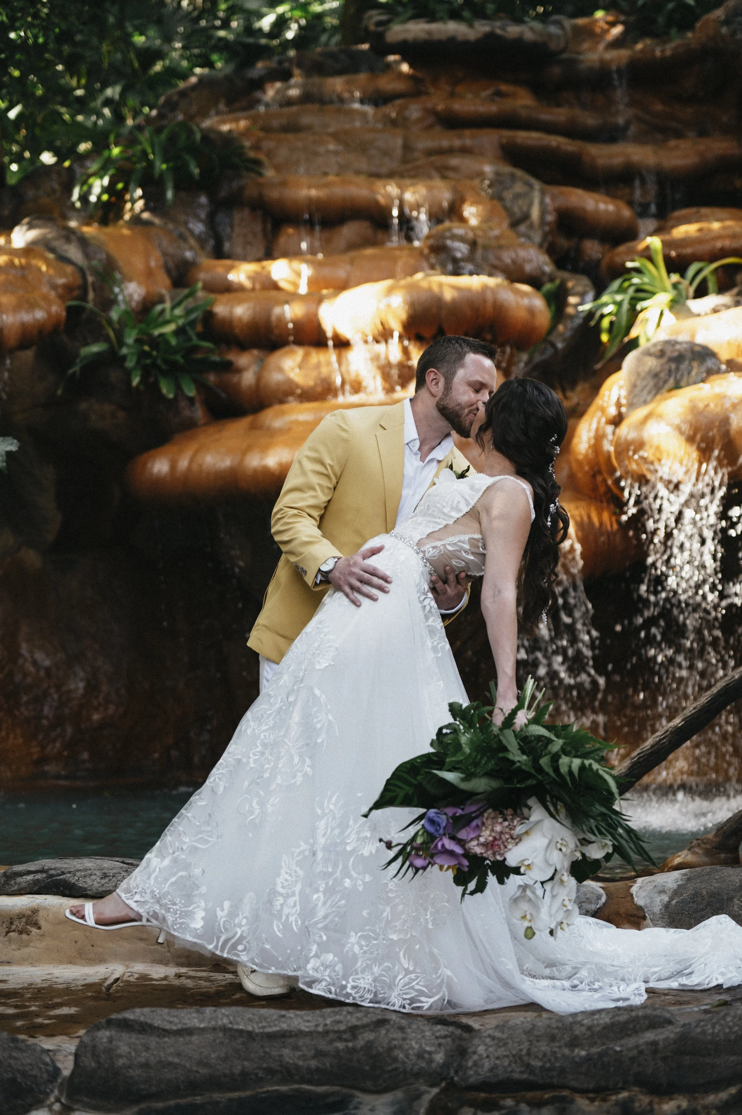 Bride and groom exchanging first kiss amidst lush greenery at rainforest wedding