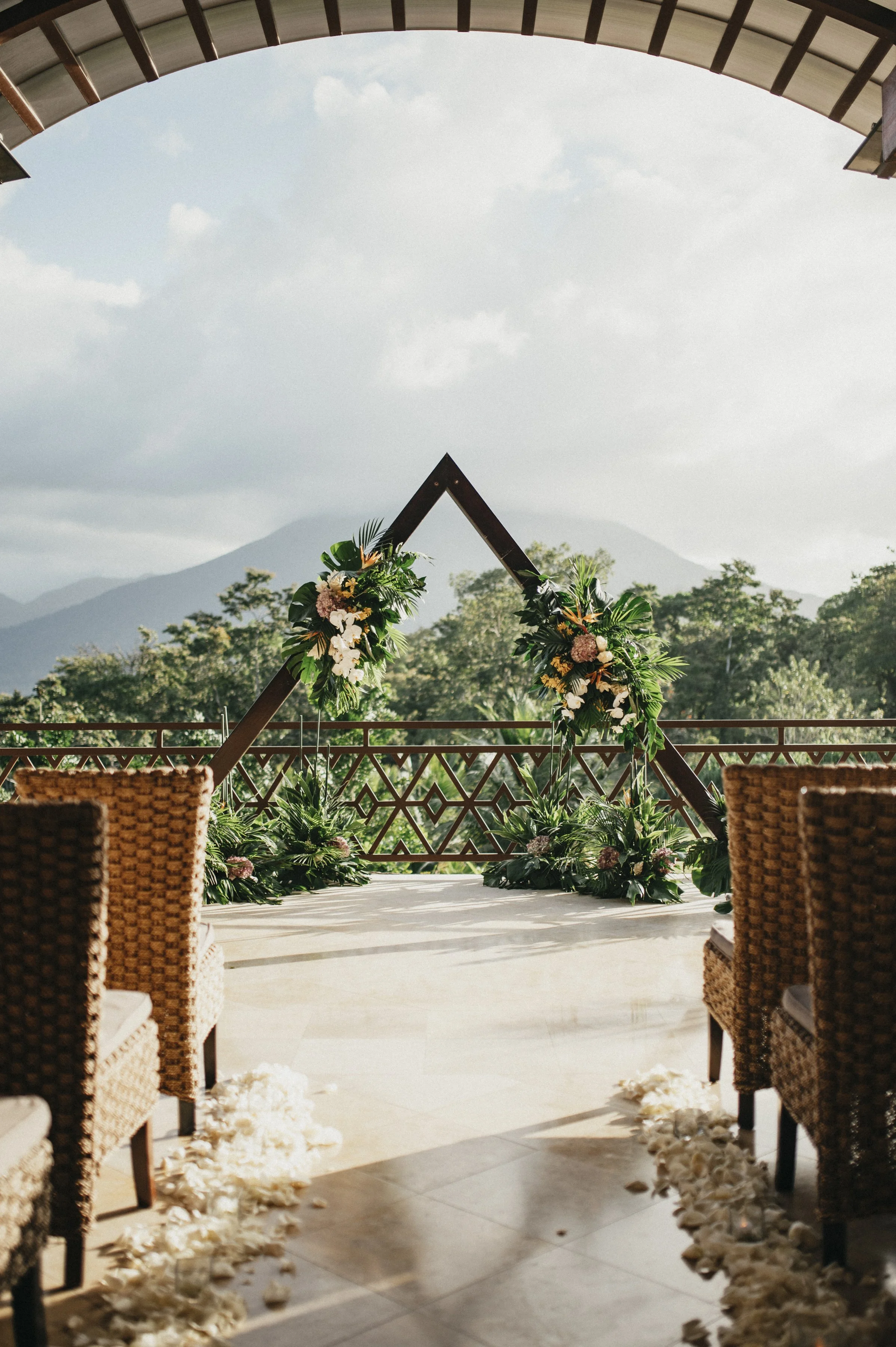 Tropical wedding arch decorated with lush greenery and tropical florals for rainforest ceremony.