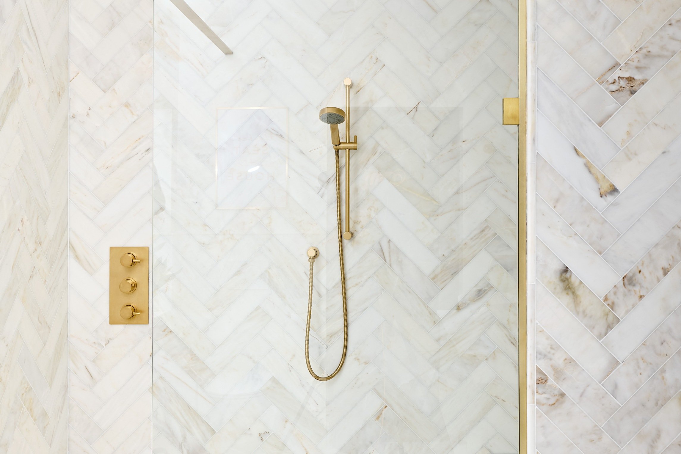 satin-gold-hand-shower-in-bathroom-with-marble-herringbone-tiles.jpg