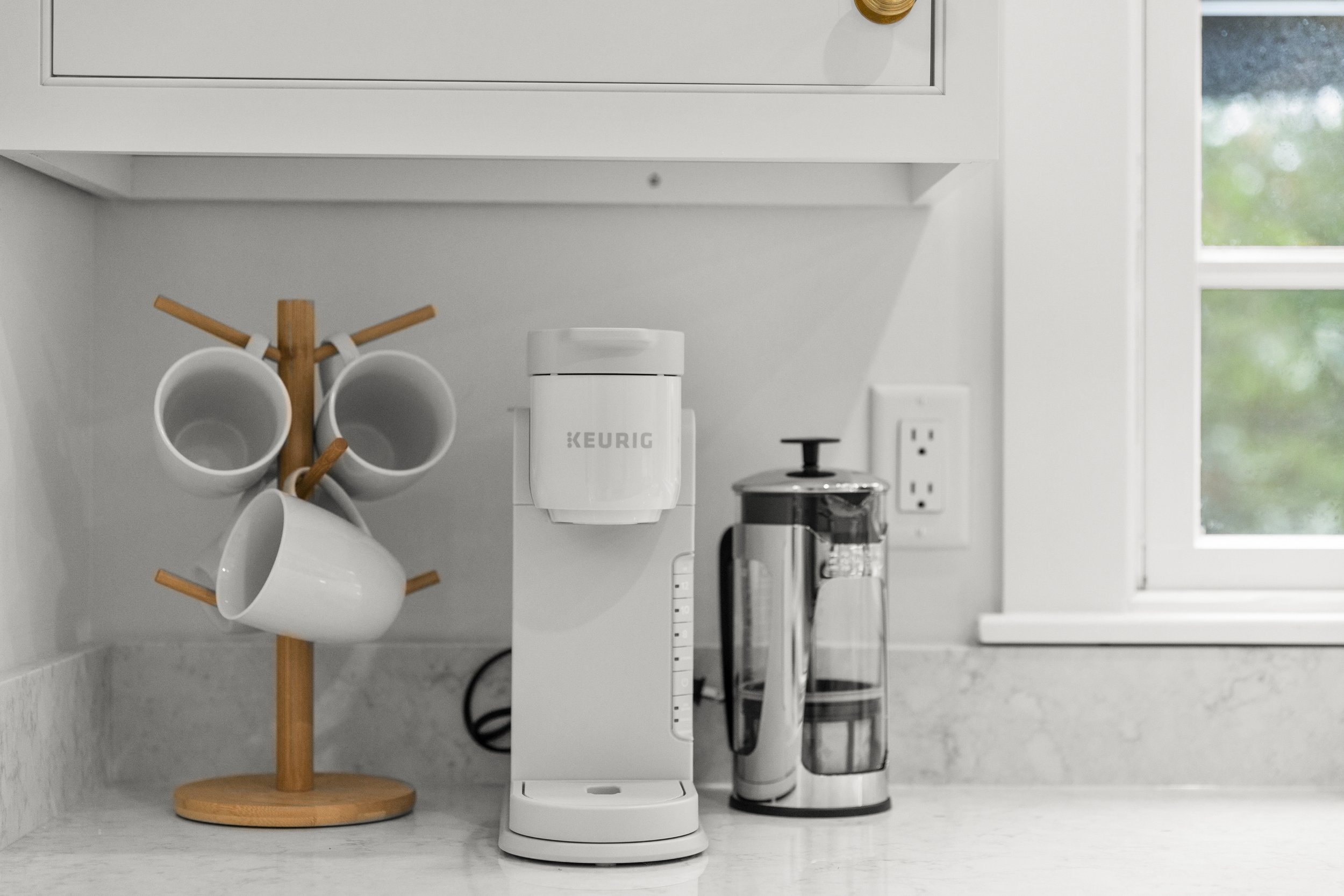Close up of Keurig coffee maker, french press, and mugs