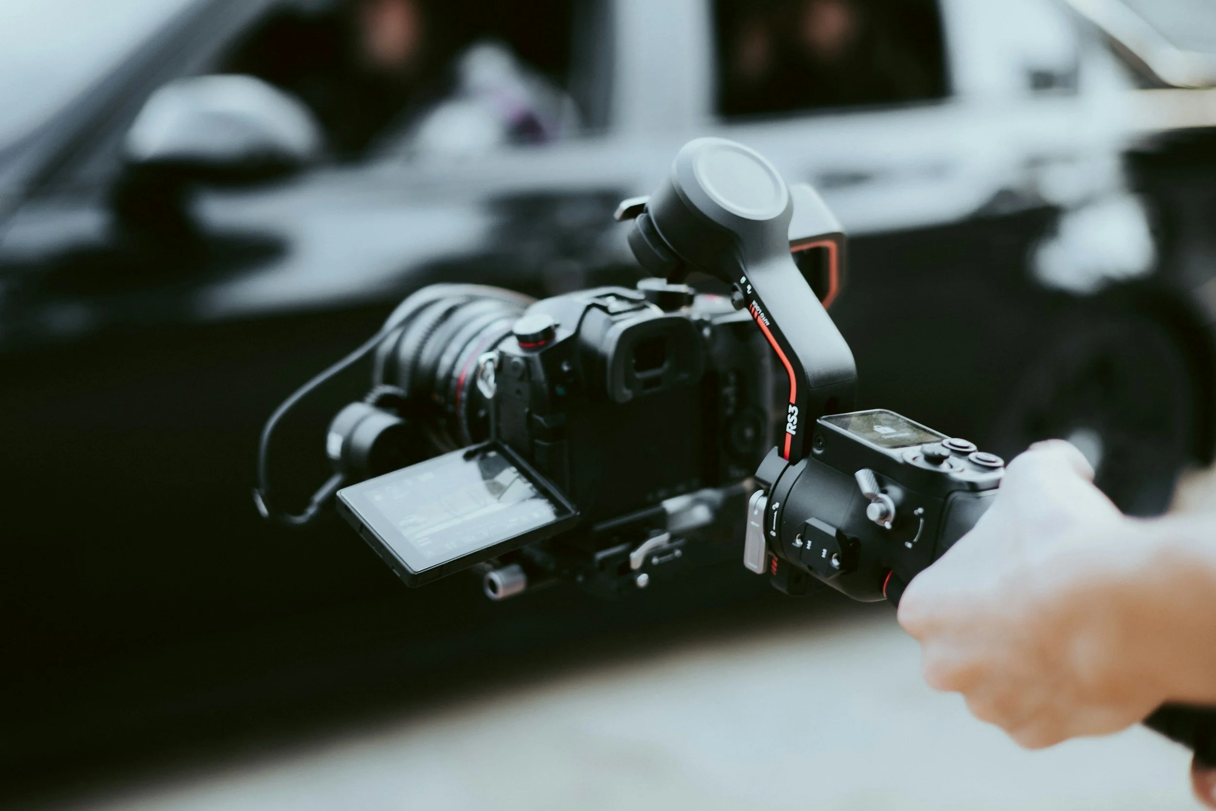 Close-up of a videographer operating a professional camera with a monitor and top-mounted microphone.