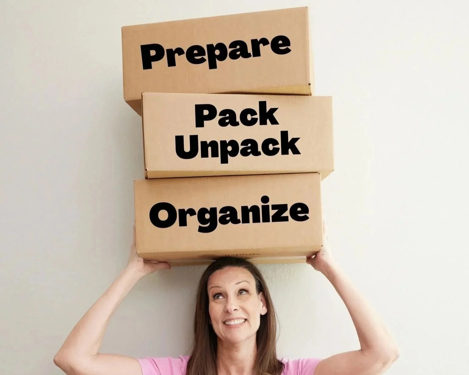 Carol Appelbaum balancing cardboard boxes labeled Prepare, Pack, Unpack, and Organize on her head.