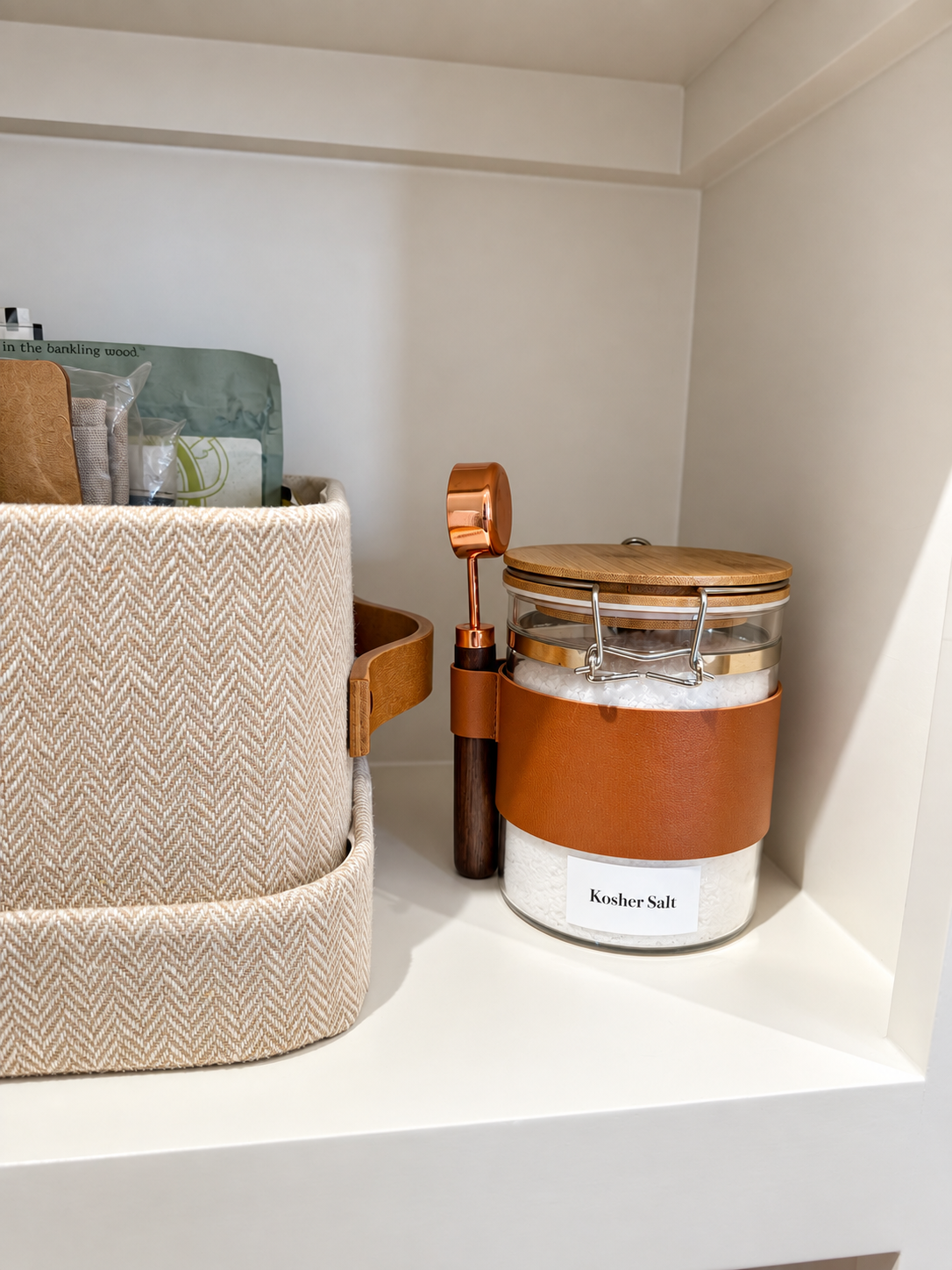 herringbone organizing bin with a canister and copper spoon next to it.